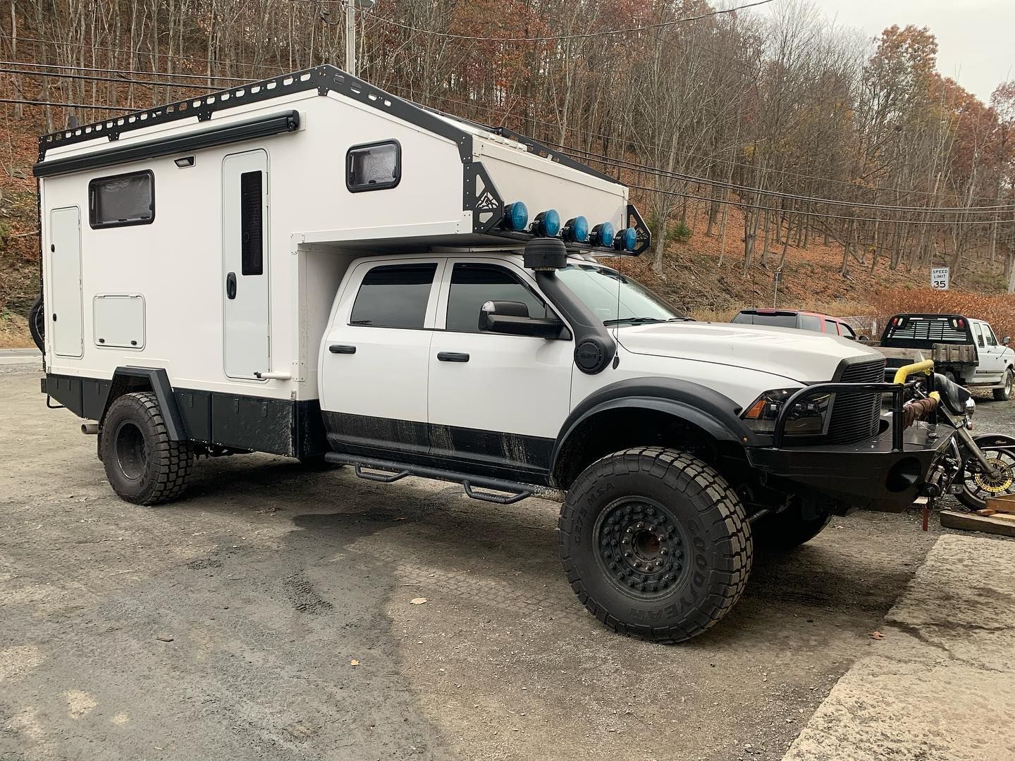 White overlanding truck with camper shell parked on a paved road. White overlanding truck with camper shell parked on a paved road.