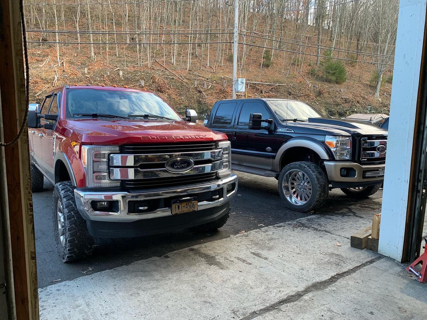 Two large pickup trucks parked in a garage; red and blue with chrome accents. Two large pickup trucks parked in a garage; red and blue with chrome accents.