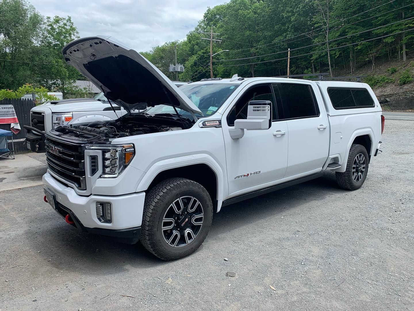White GMC truck with hood open, parked outdoors on gravel. White GMC truck with hood open, parked outdoors on gravel.