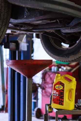 Open truck hood with engine visible, oil bottles in a basket. Tools and other trucks are also in frame. Open truck hood with engine visible, oil bottles in a basket. Tools and other trucks are also in frame.