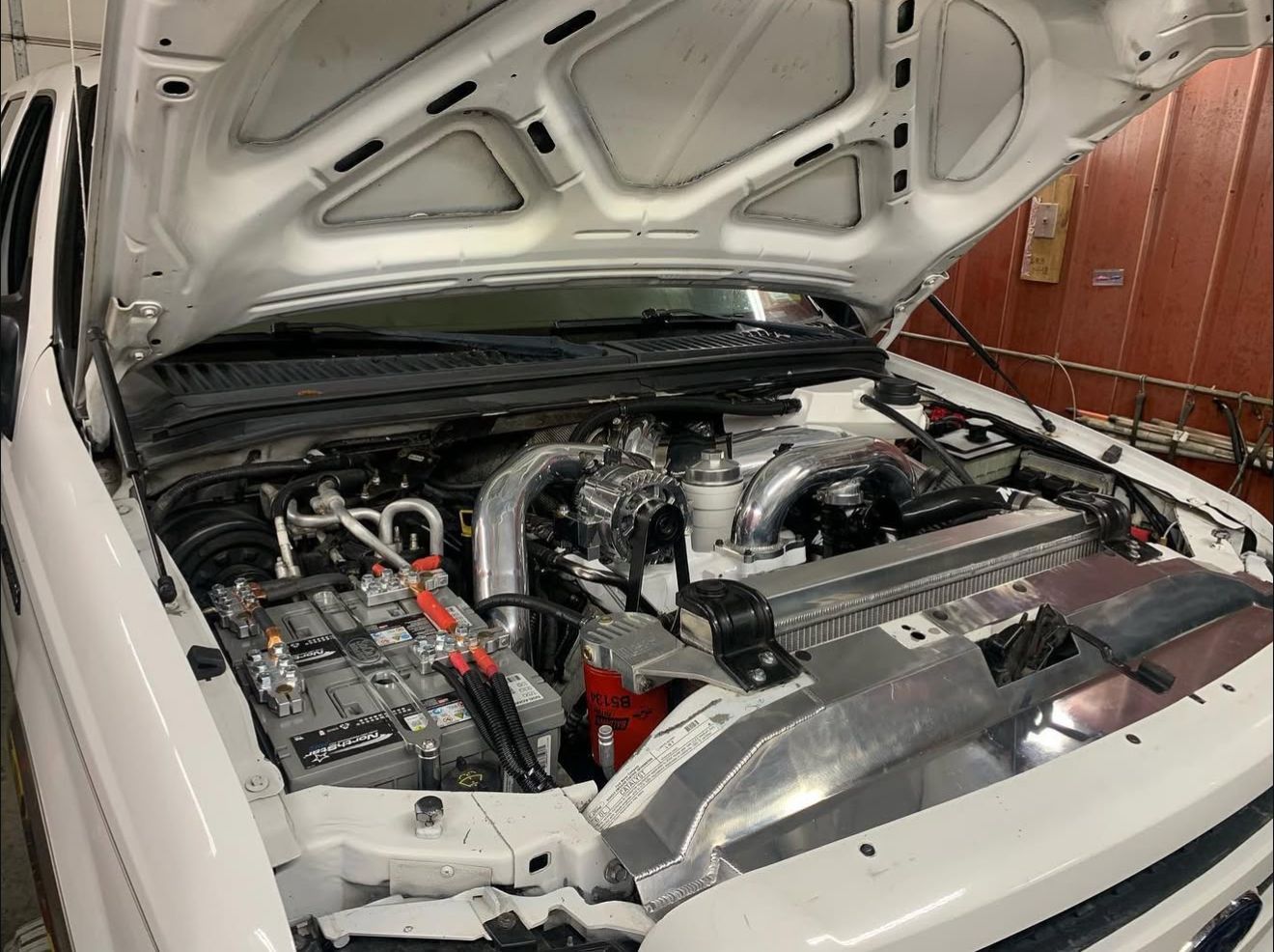 Blue Jeep CJ-7 with black top and large tires, parked on a gravel surface.