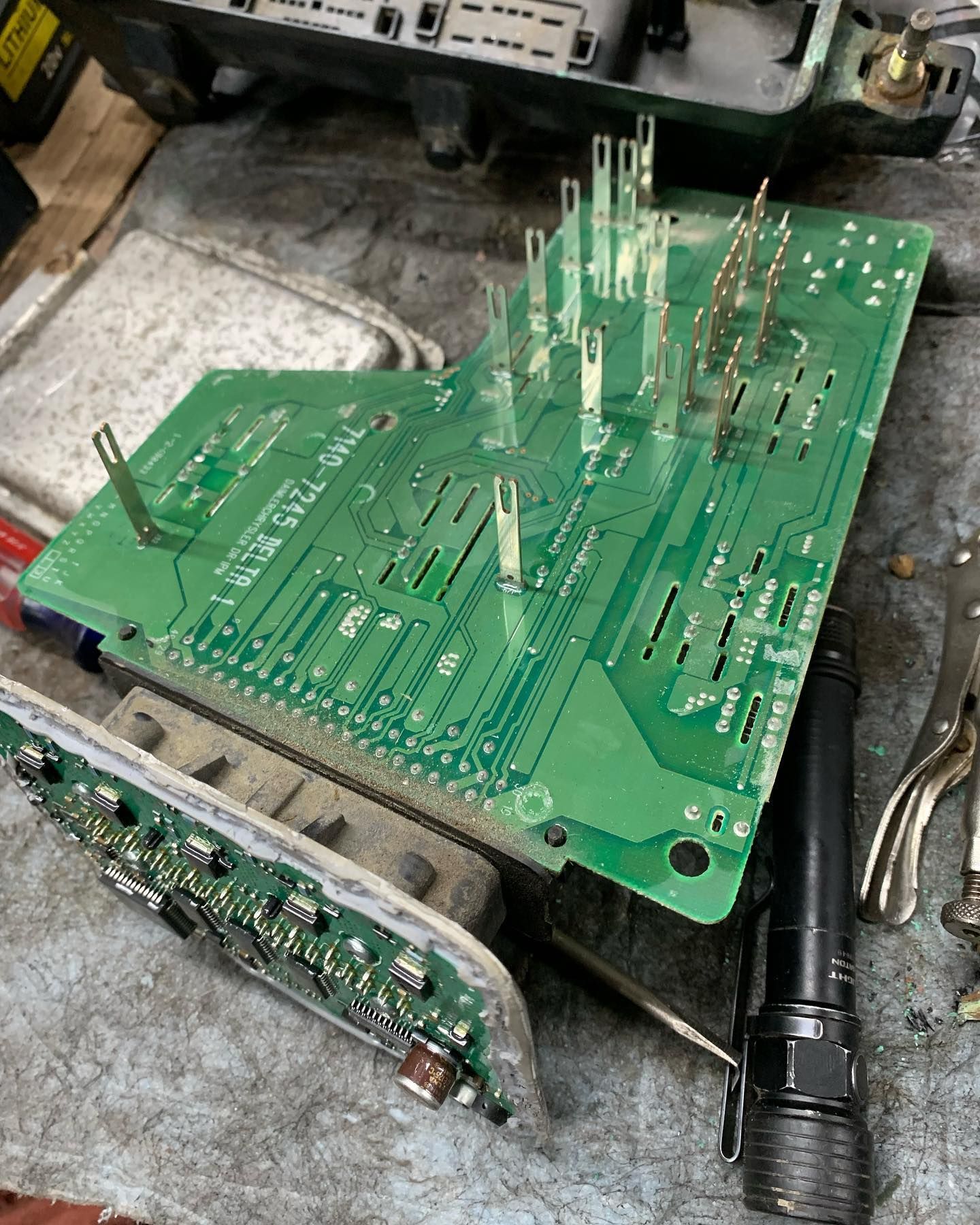 Green circuit board with pins, next to a small circuit board and a flashlight. Green circuit board with pins, next to a small circuit board and a flashlight.