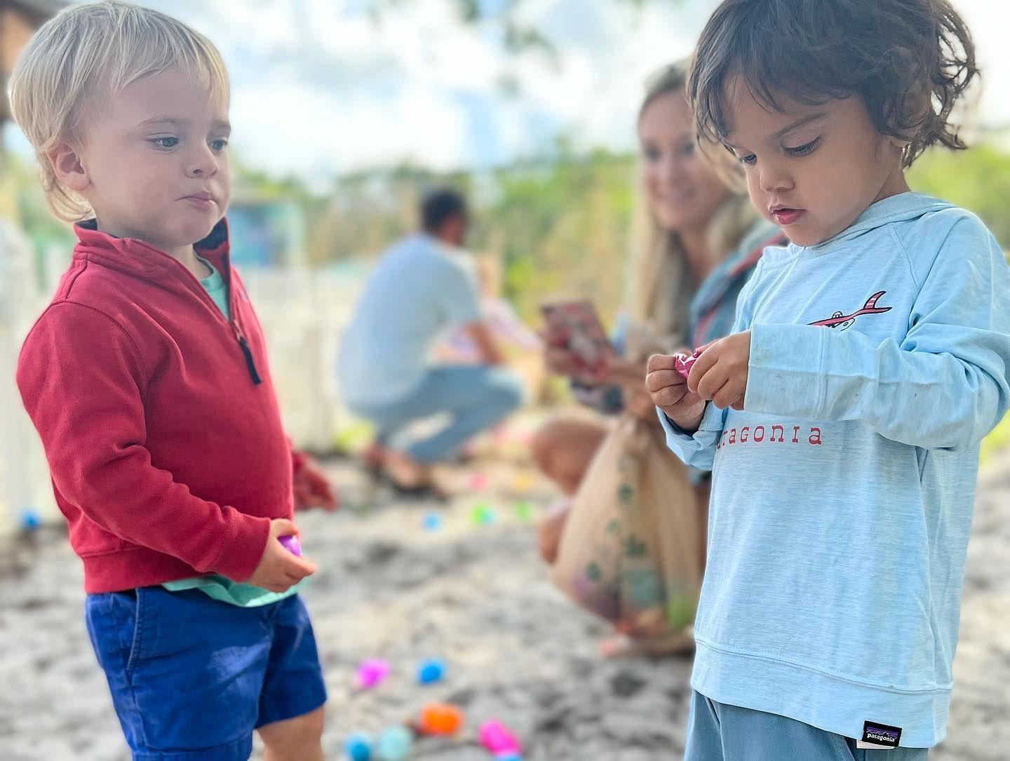 Two young boys are standing next to each other on a beach.