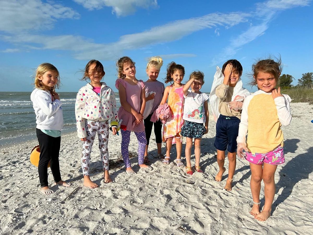 A group of children are standing on a sandy beach.