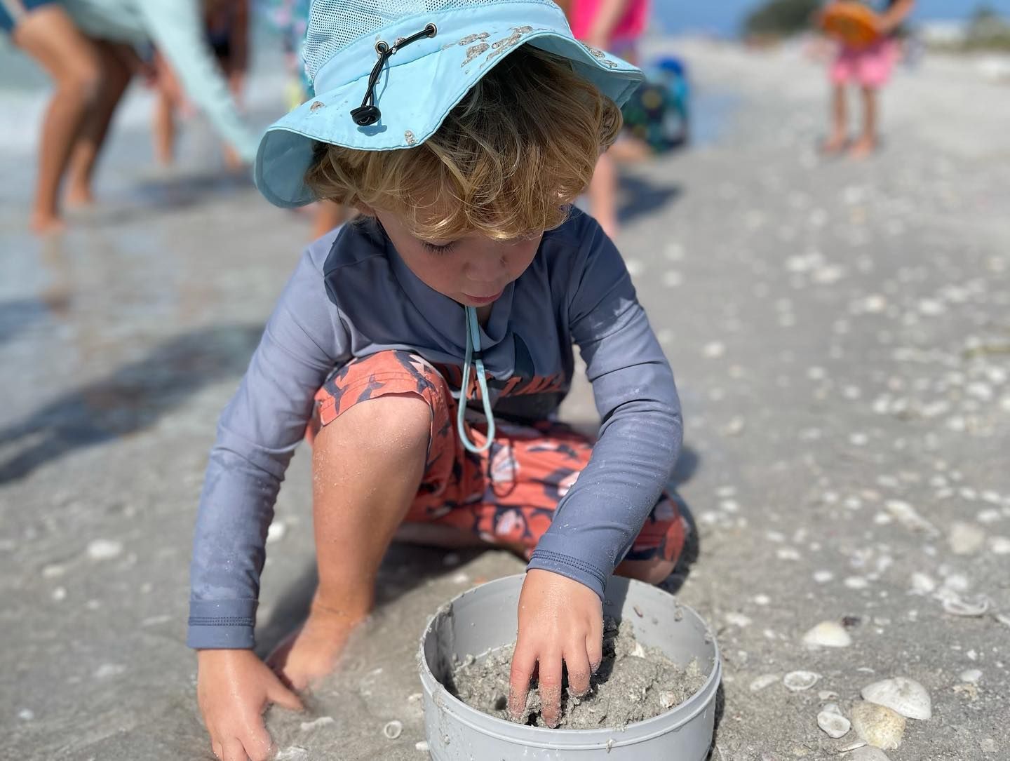 A young boy is playing in the sand on the beach.