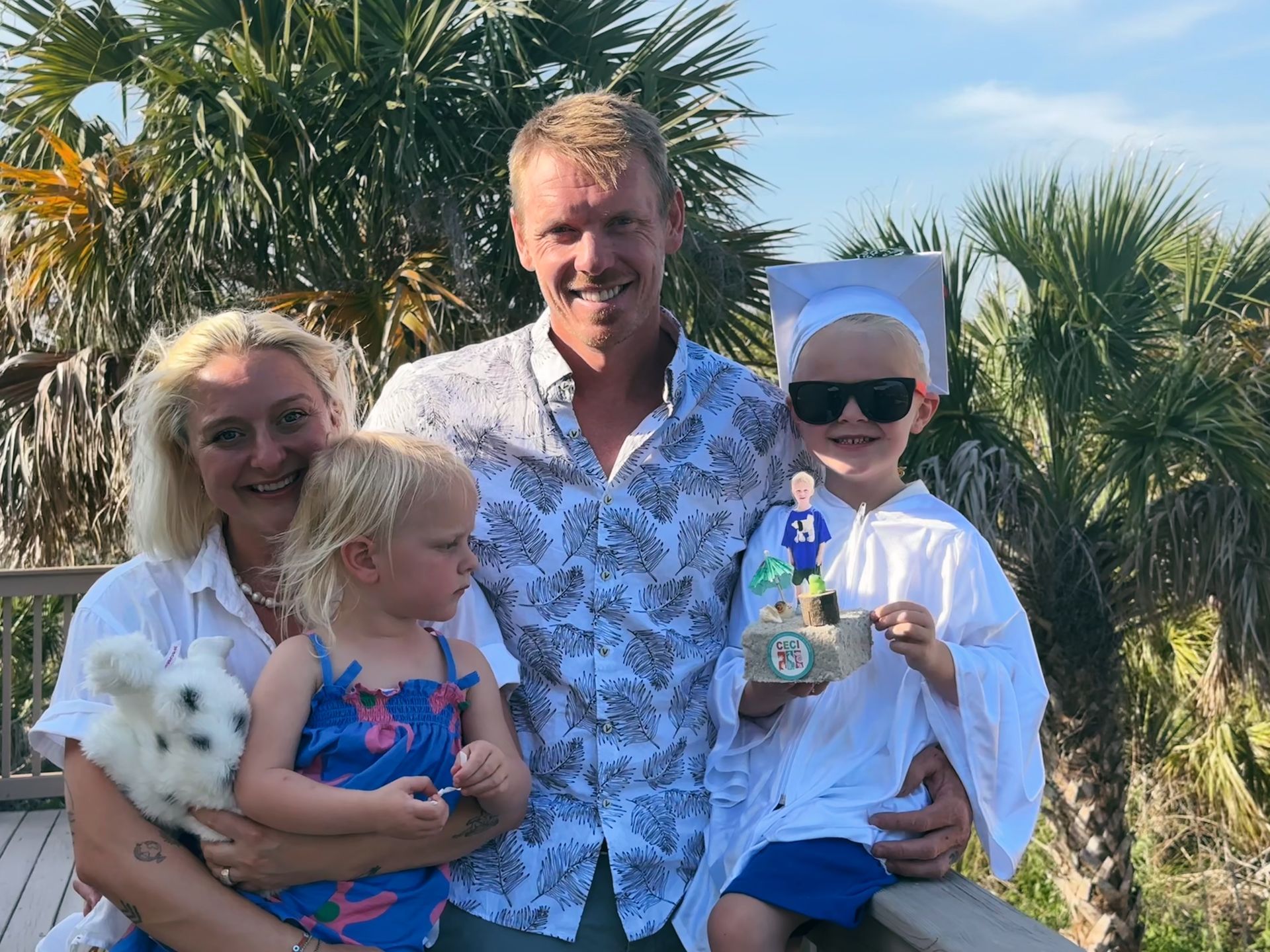 A woman and two children are sitting on a red picnic table.