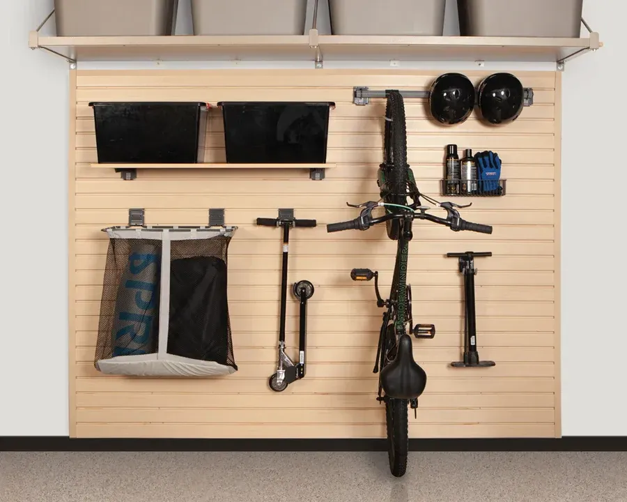 Garage organization system with storage bins, bike, scooter, and accessories on a wooden panel wall.
