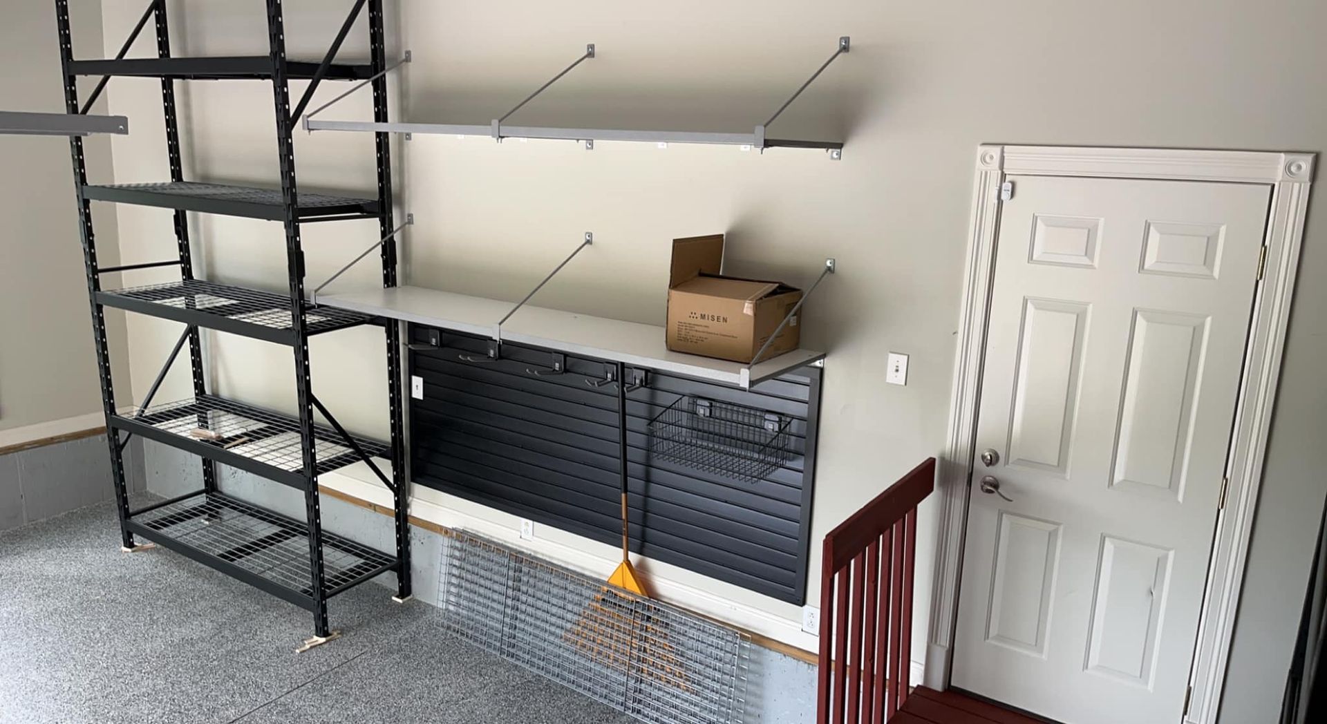 Garage storage unit with shelves and pegboard, broom, and a door.