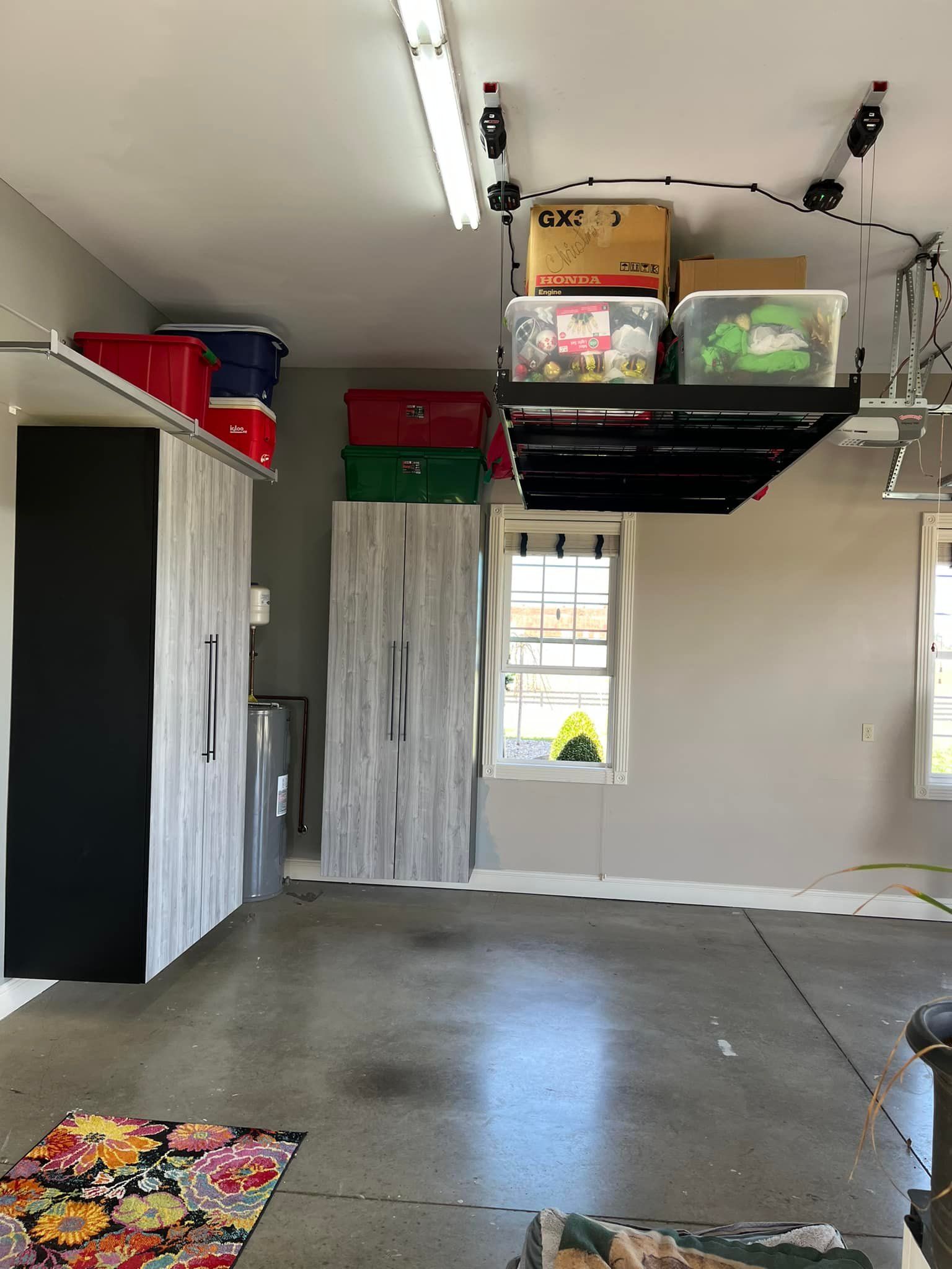 Garage with storage cabinets, overhead shelf with boxes, and concrete floor.