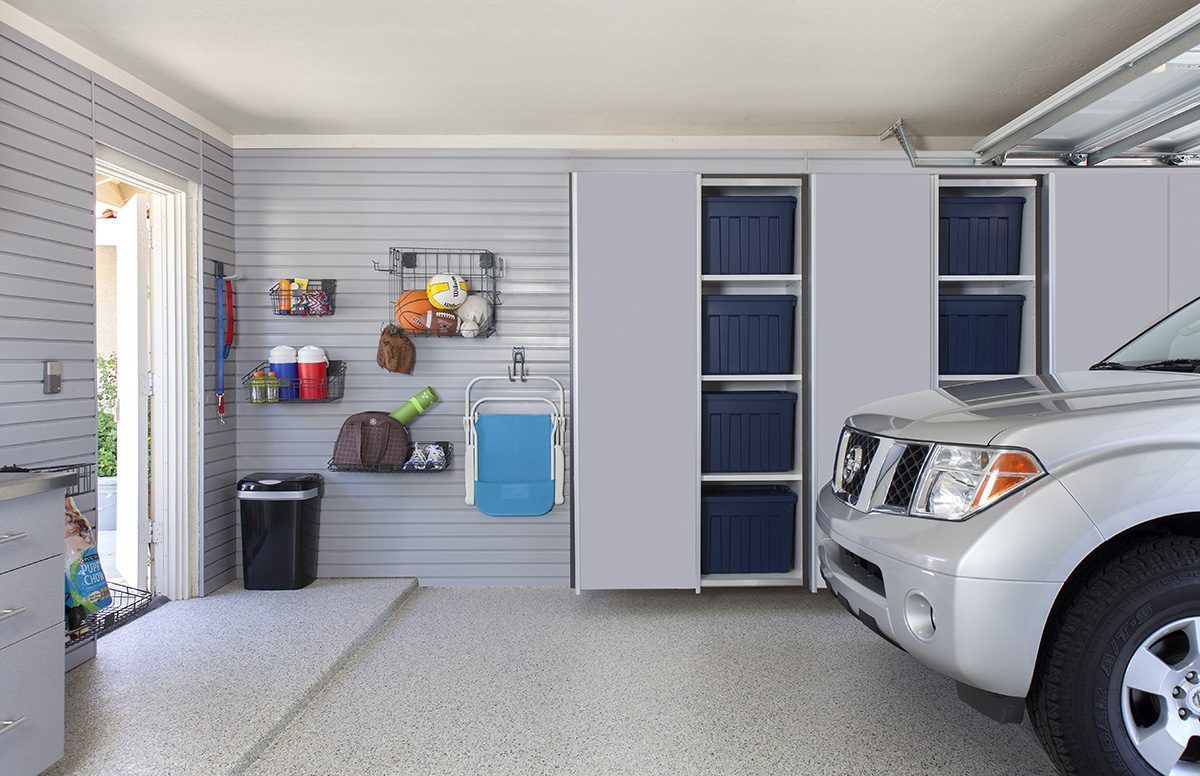 Garage interior with a silver SUV, storage cabinets, and various items on shelves.