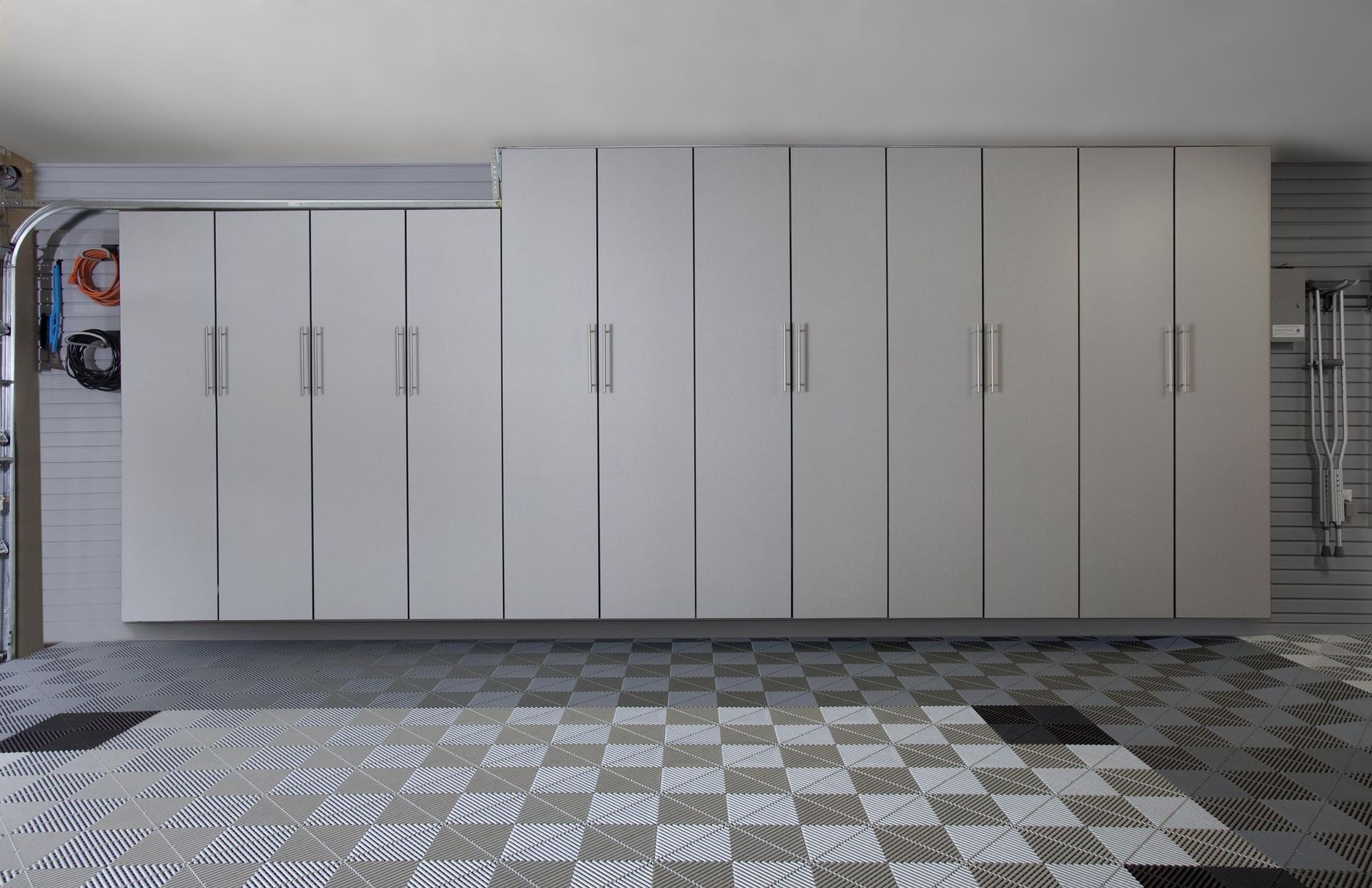 White garage cabinets above a checkerboard floor, next to a garage door.