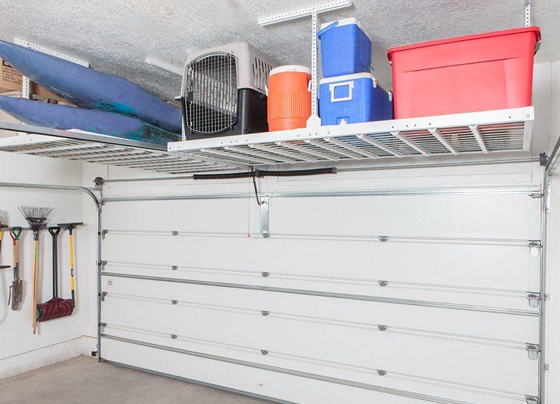 Overhead storage in a garage holds kayak, coolers, and storage bins above a closed garage door.