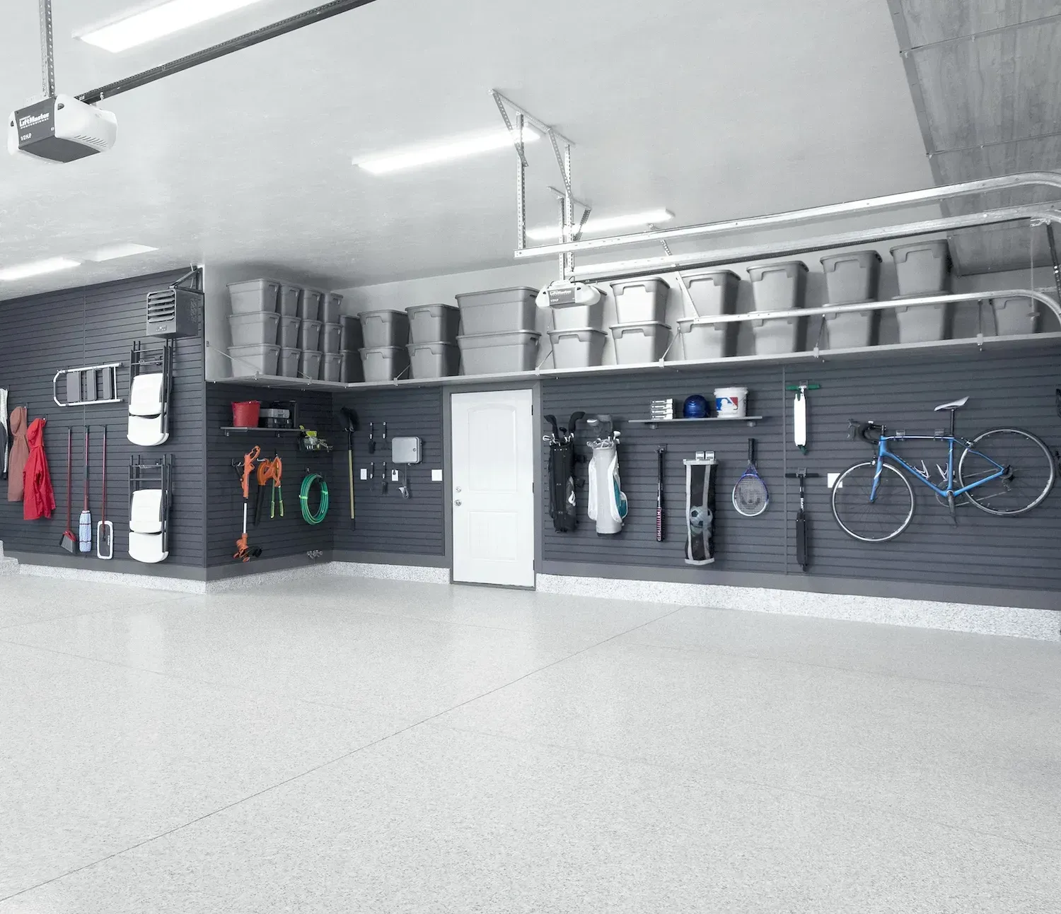 Clean, organized garage with gray walls, storage racks, and a white door. Concrete floor.