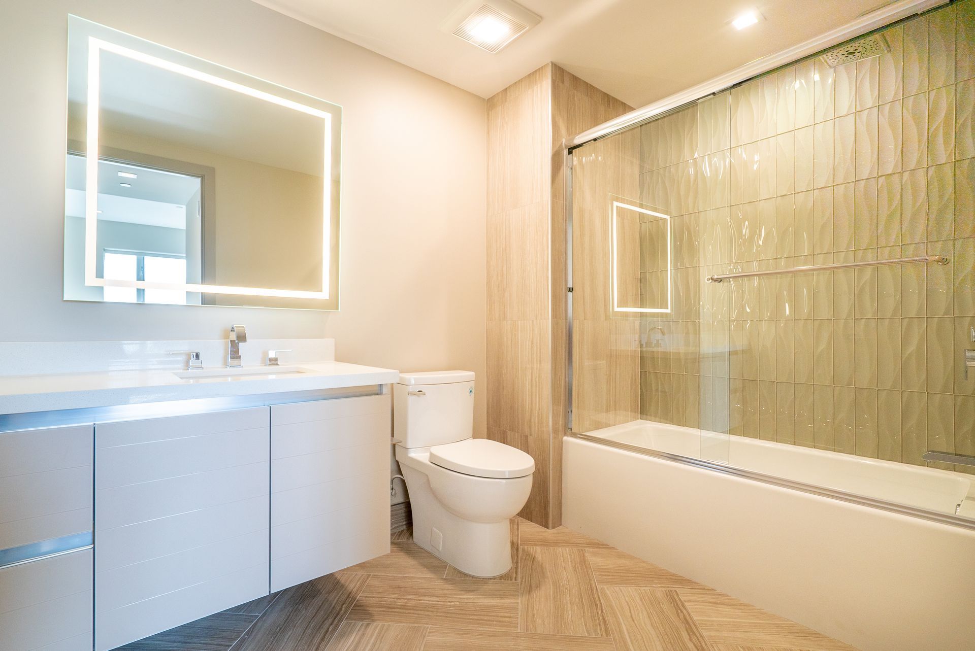 Modern bathroom with a white vanity, toilet, and bathtub. Beige tiles and a large mirror.