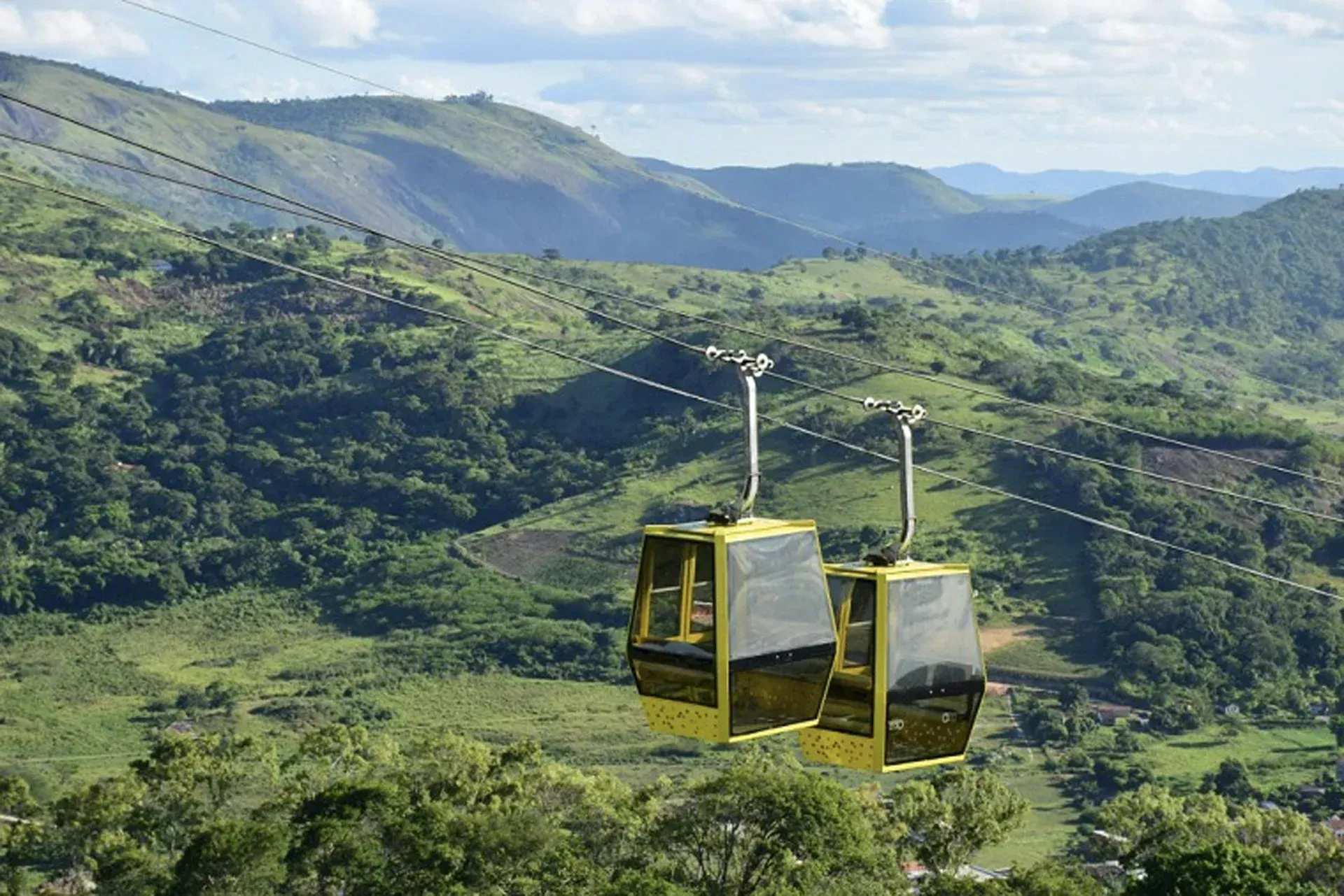 Um teleférico está passando por uma encosta verdejante.