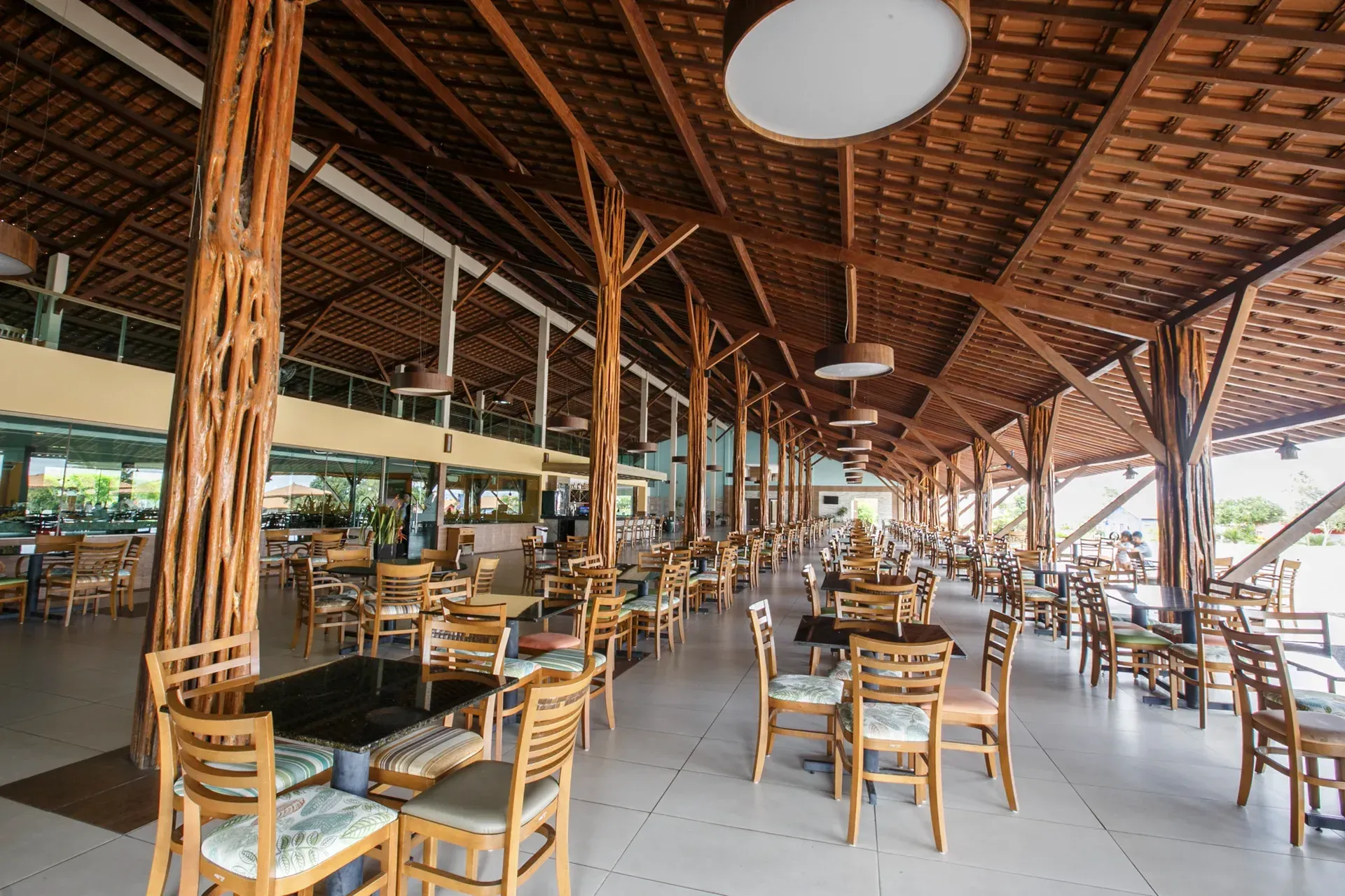 Um restaurante com mesas e cadeiras sob um teto de madeira