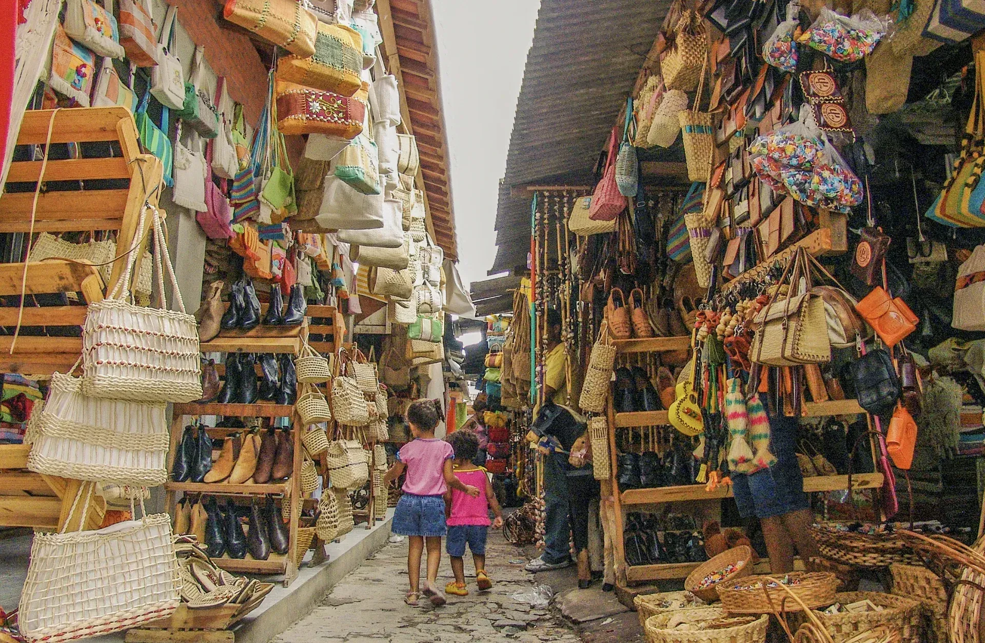Um casal de crianças está caminhando por uma rua estreita em um mercado.