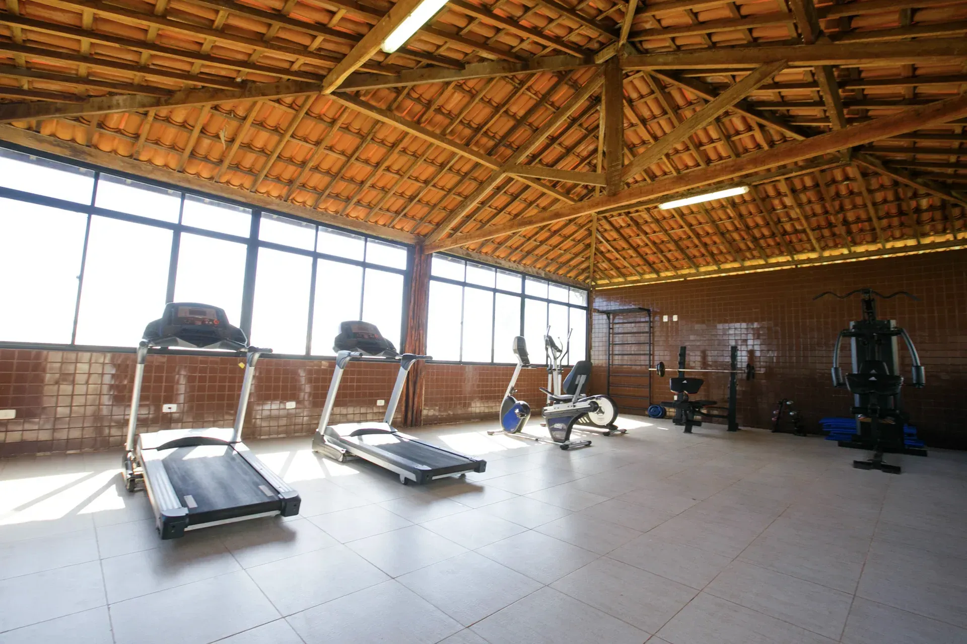 Uma academia com esteiras e uma fileira de janelas