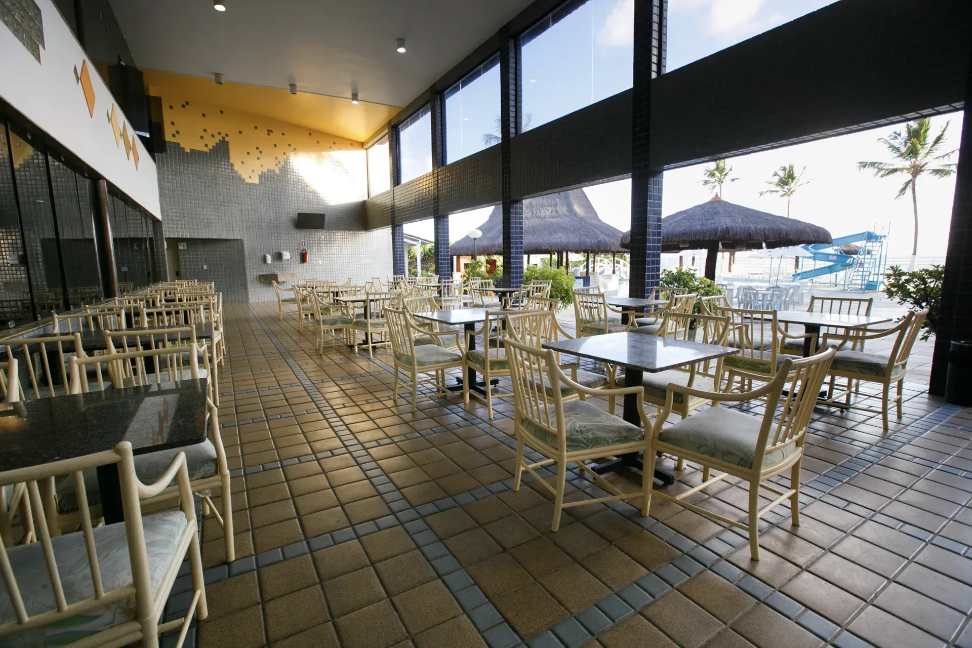 Um restaurante com mesas e cadeiras e um toboágua ao fundo