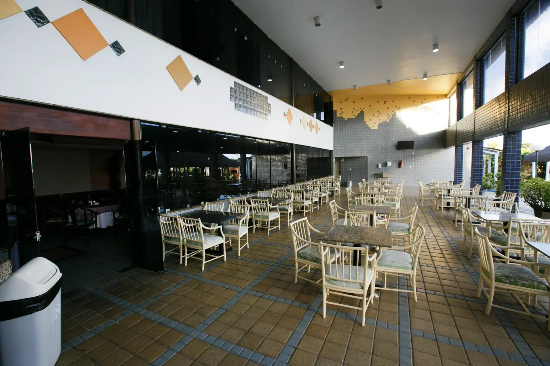 Um restaurante com mesas e cadeiras e uma lata de lixo