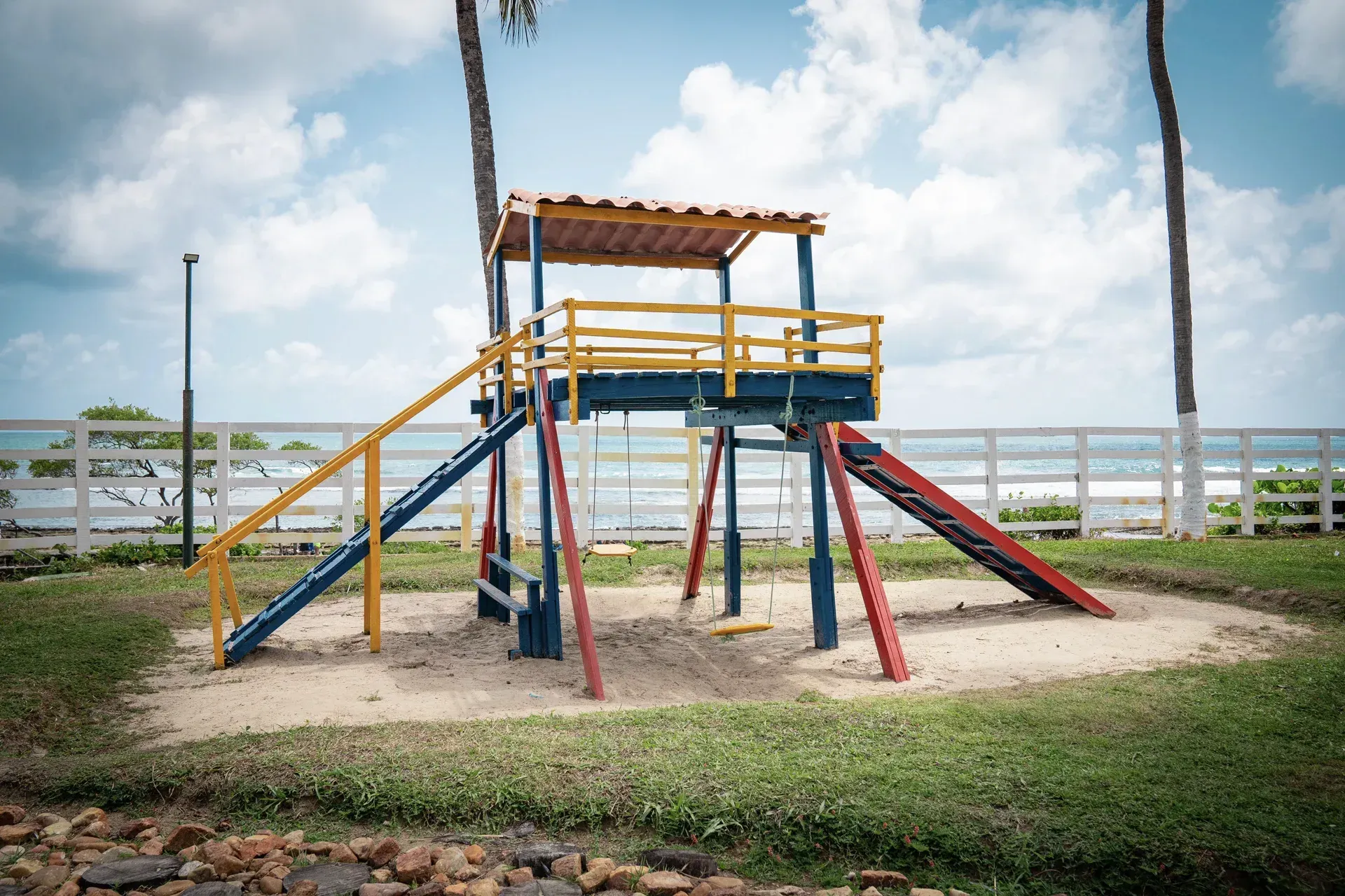 Um playground colorido com escadas e balanços em uma área gramada.