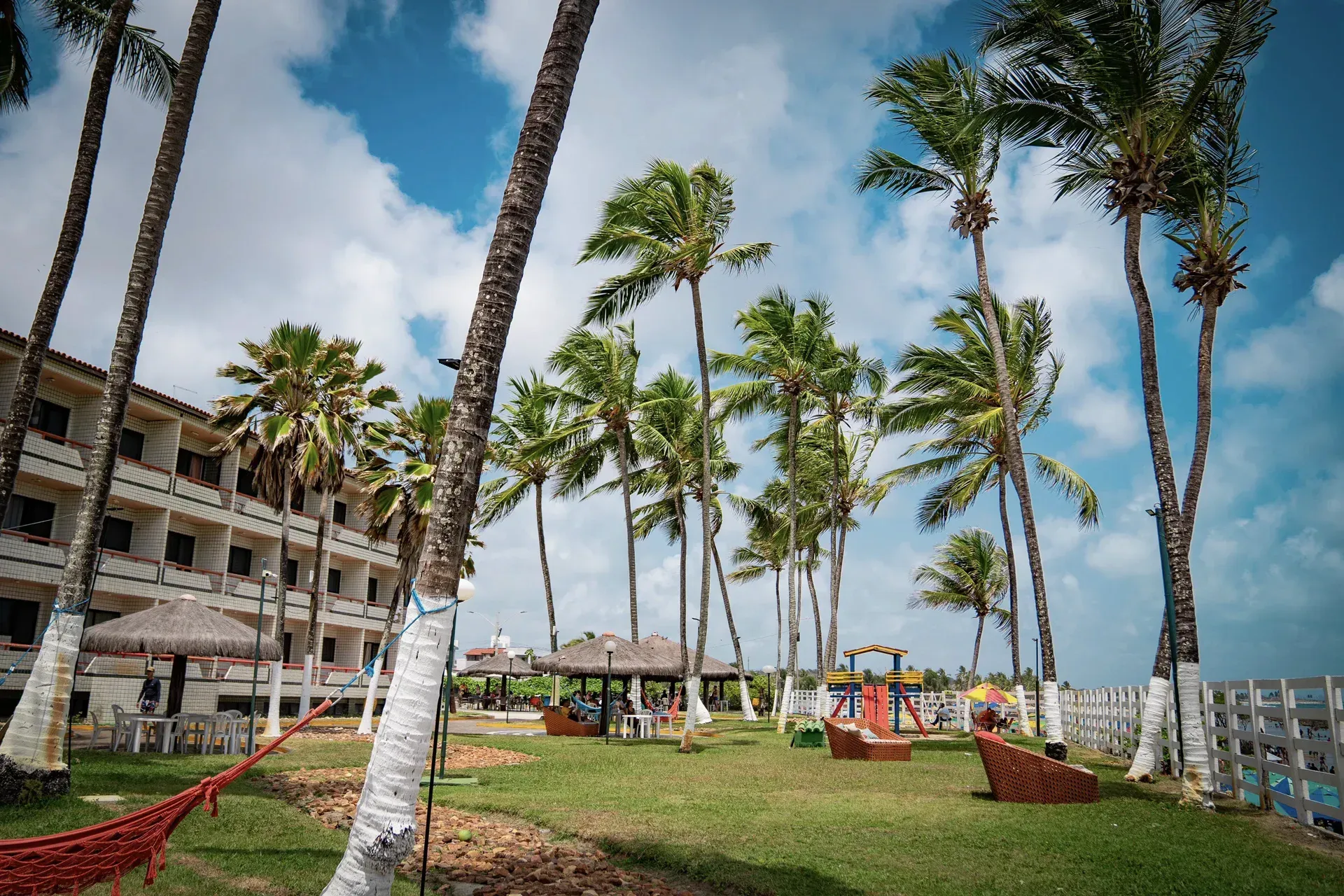 Uma fileira de palmeiras em frente a um prédio em um dia ensolarado.