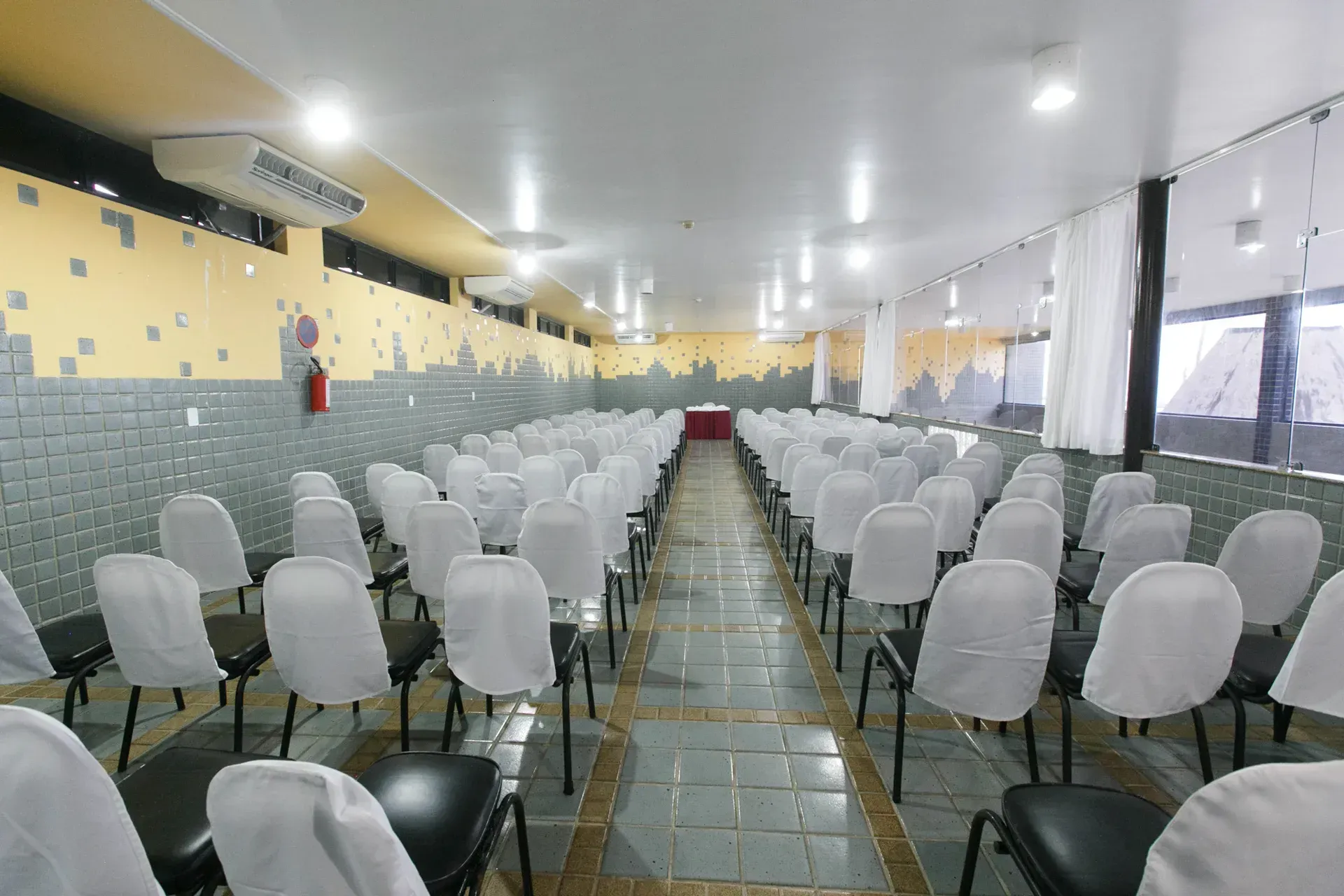 Uma longa fileira de cadeiras brancas em uma sala grande.