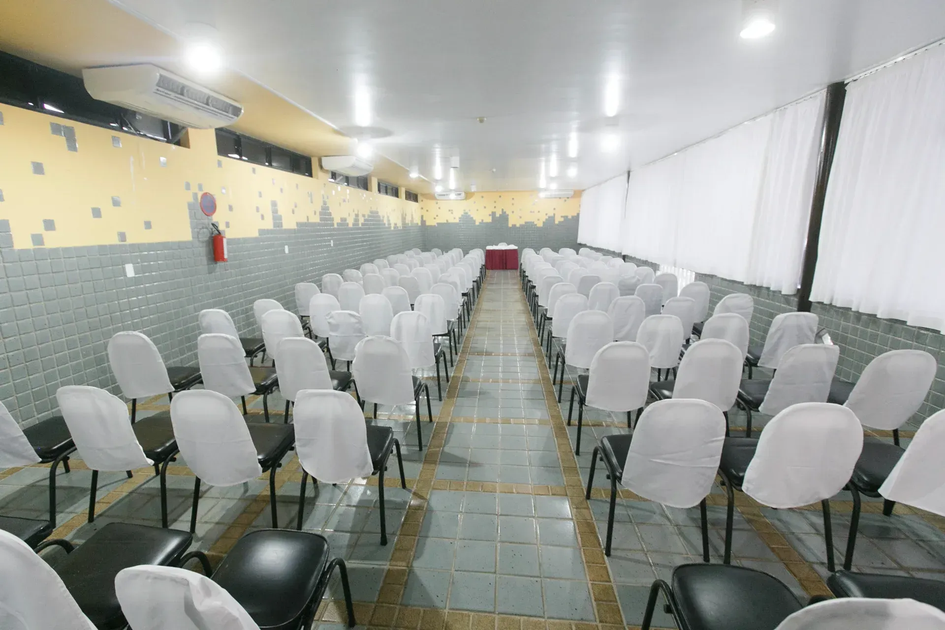 Uma longa fileira de cadeiras brancas em uma sala de conferências.