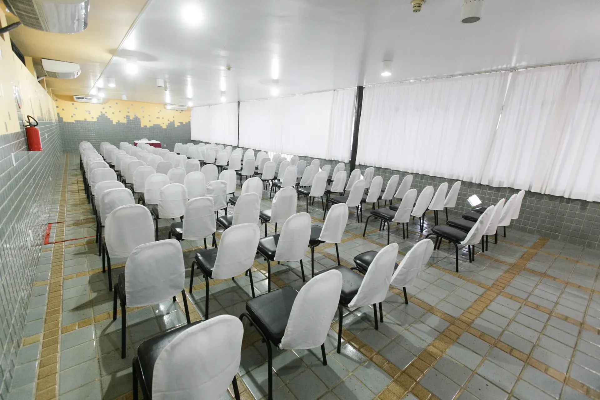 Uma sala grande com fileiras de cadeiras e mesas.
