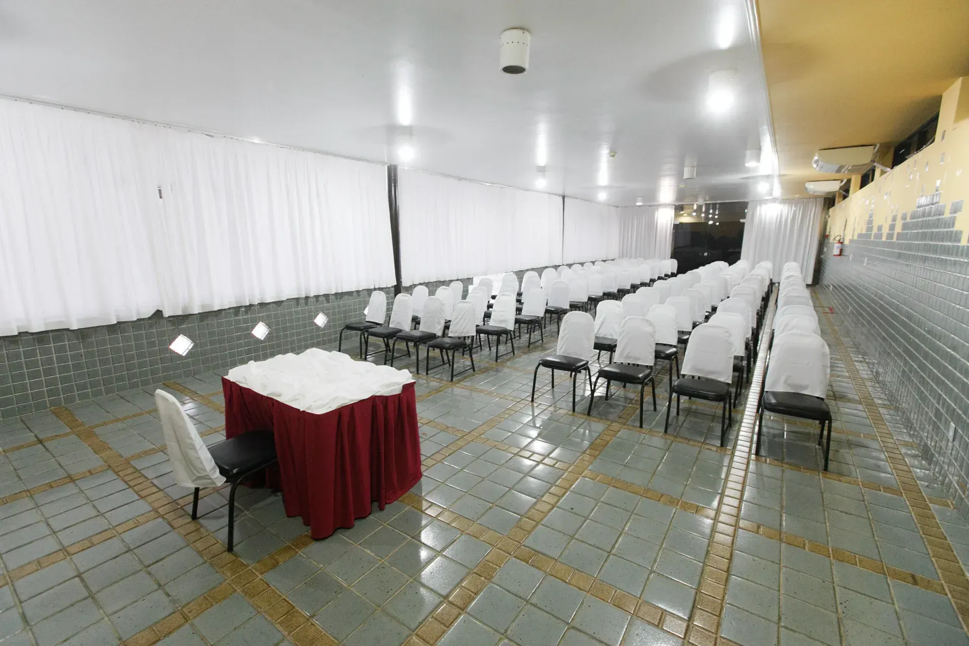 Uma sala grande com fileiras de cadeiras e uma mesa.