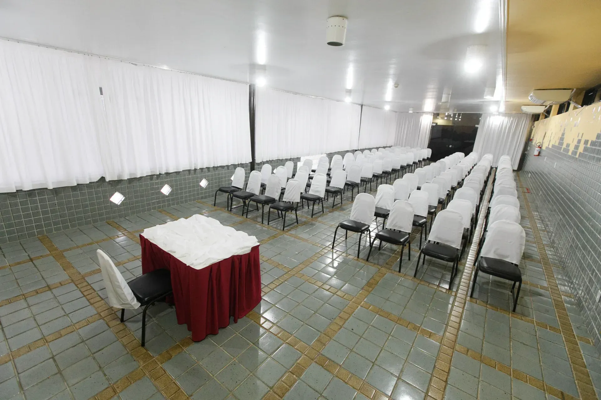 Uma sala grande com fileiras de cadeiras e uma mesa.