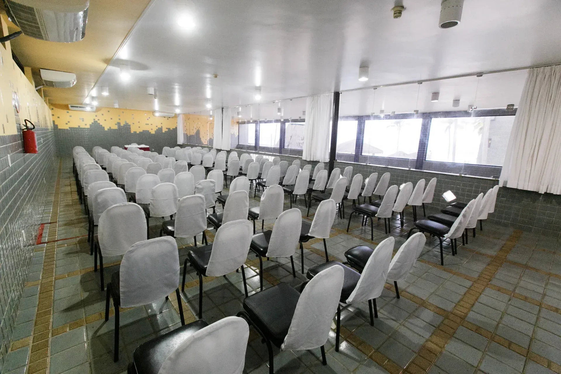 Uma grande sala cheia de fileiras de cadeiras e mesas.