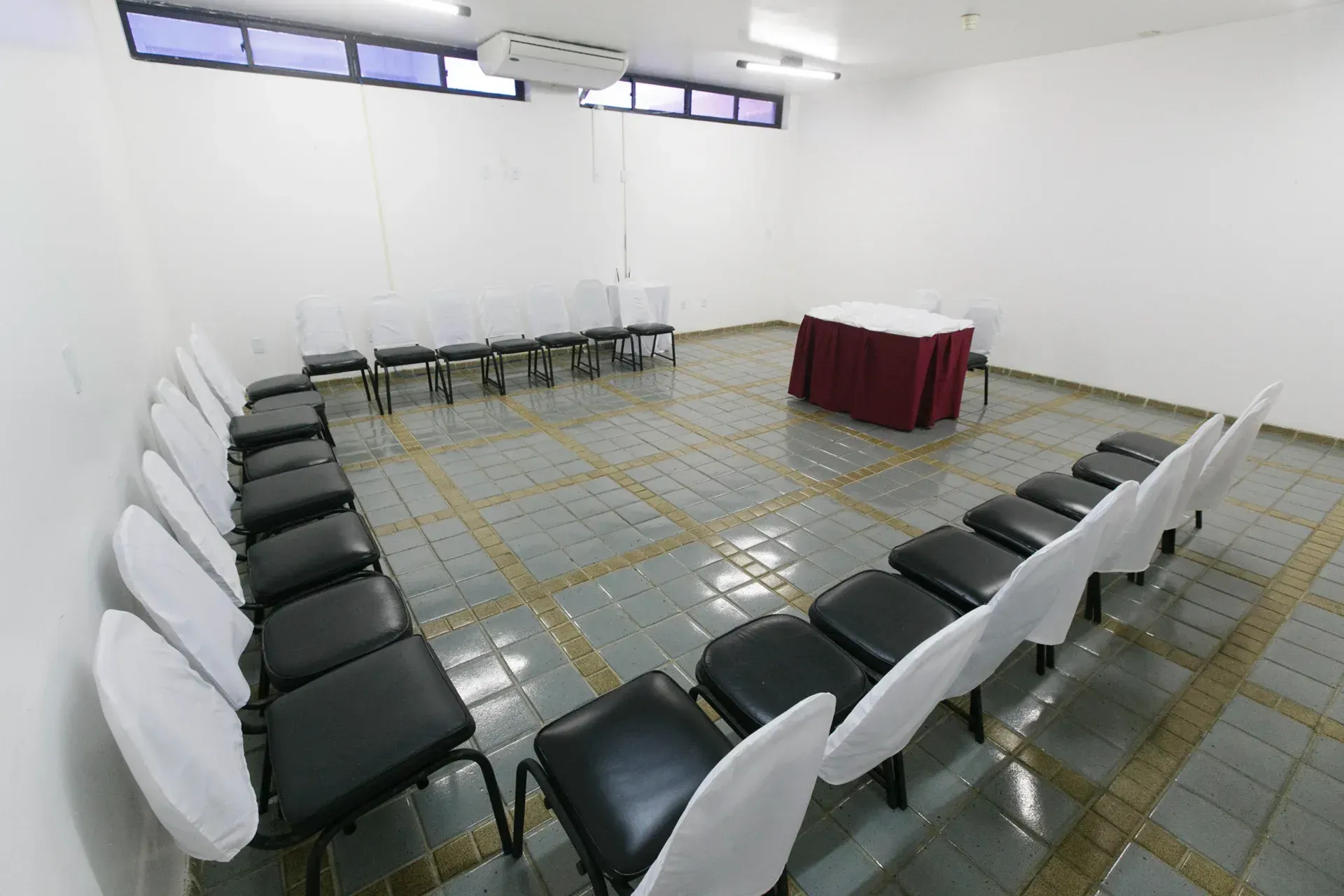 Uma sala com fileiras de cadeiras e uma mesa no meio