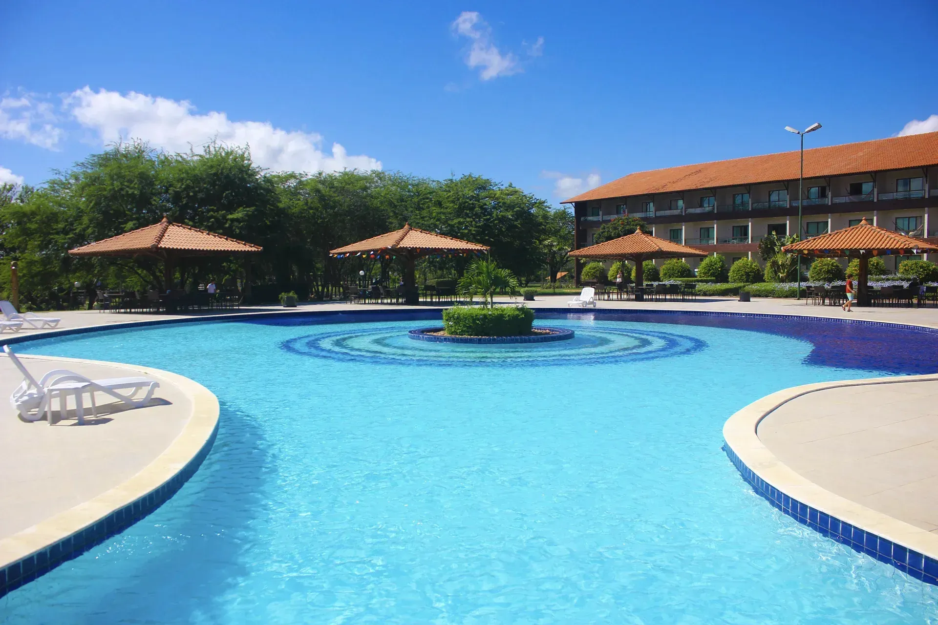 Uma grande piscina com guarda-sóis e cadeiras ao redor