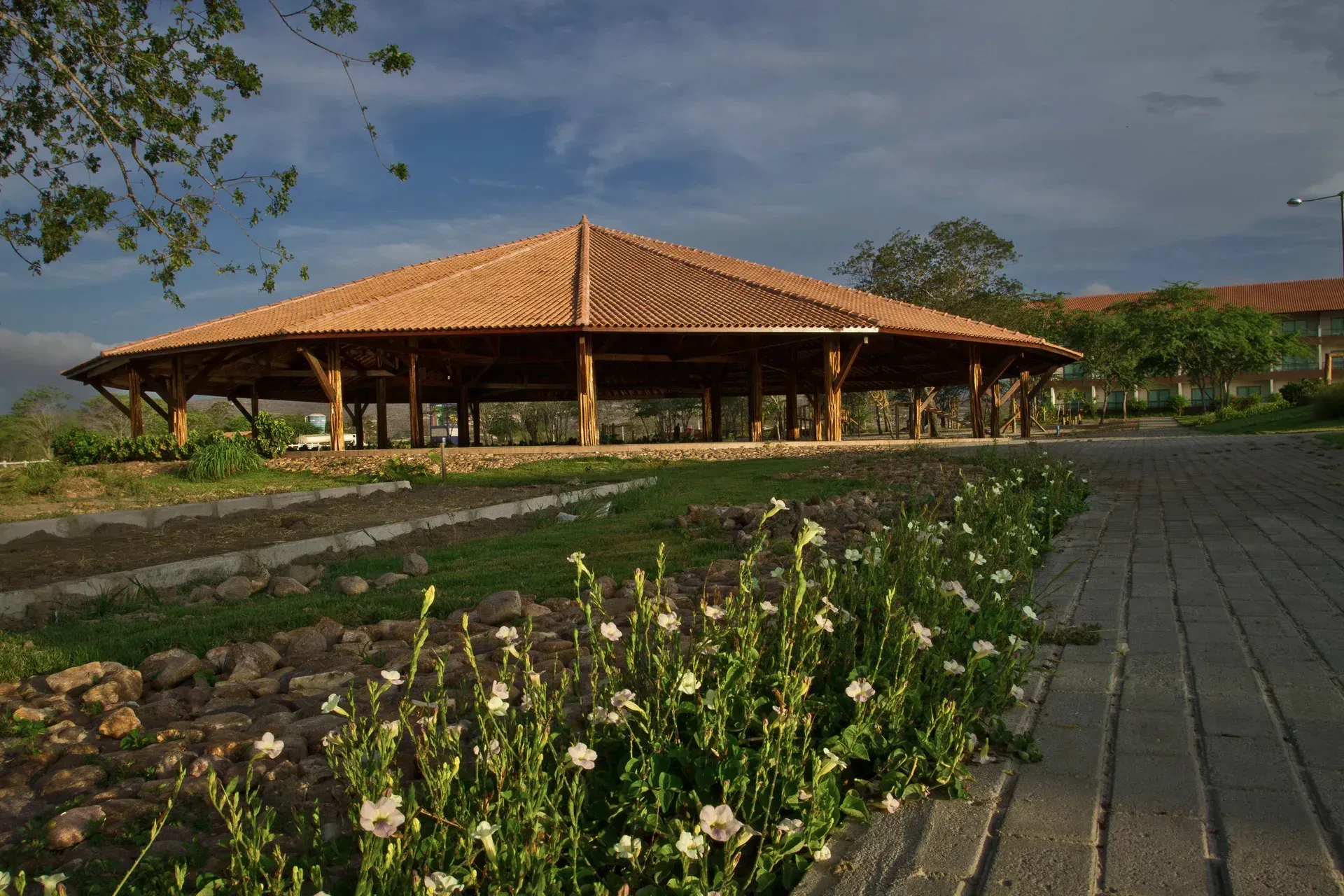 Um grande edifício com telhado de telhas cercado por flores e grama.