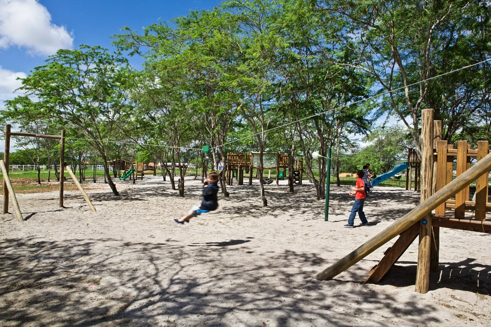 Uma mulher está sentada em um balanço em um playground.