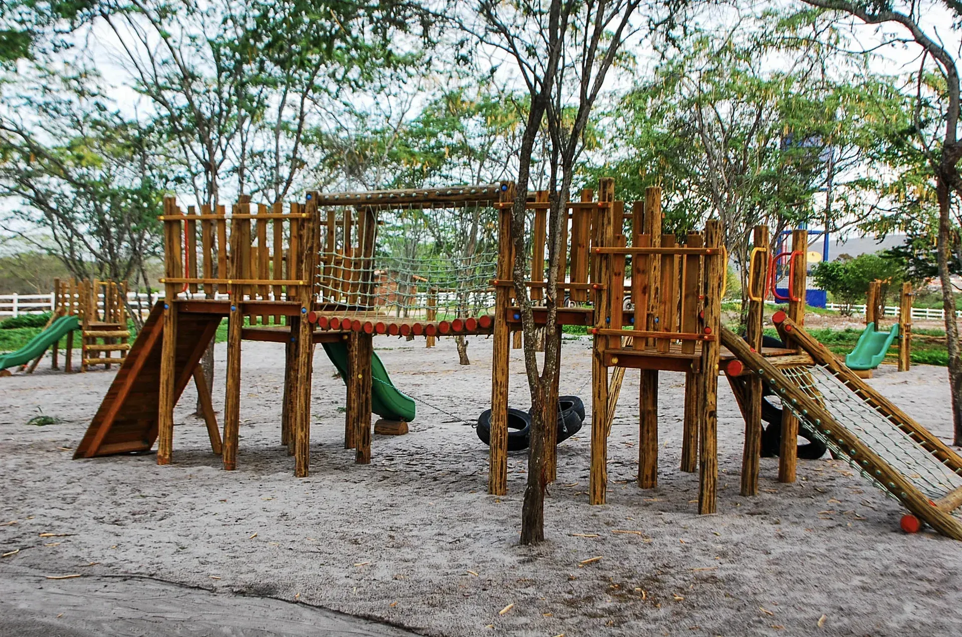 Um playground de madeira em um parque com árvores ao fundo