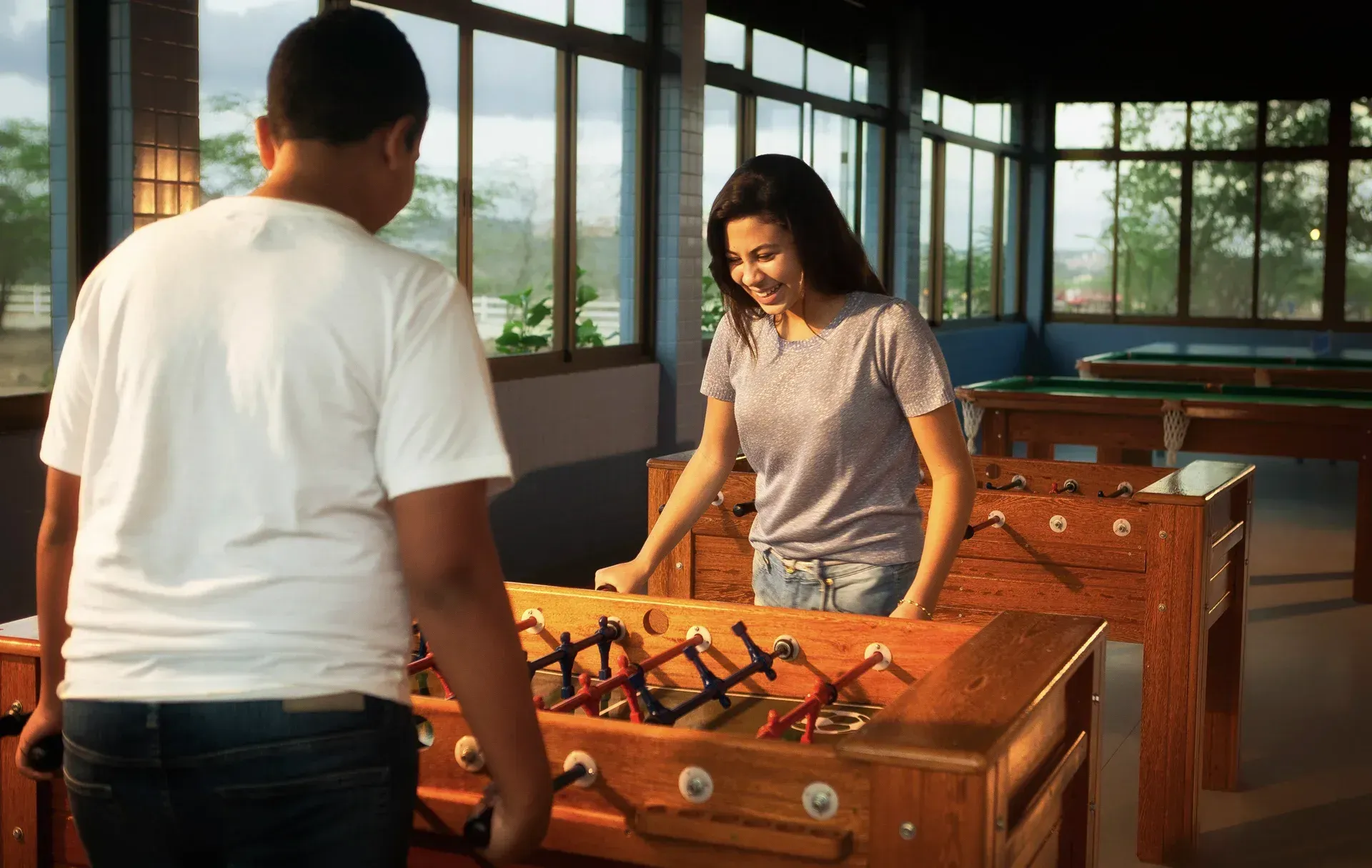 Um homem e uma mulher estão jogando pebolim em uma sala.