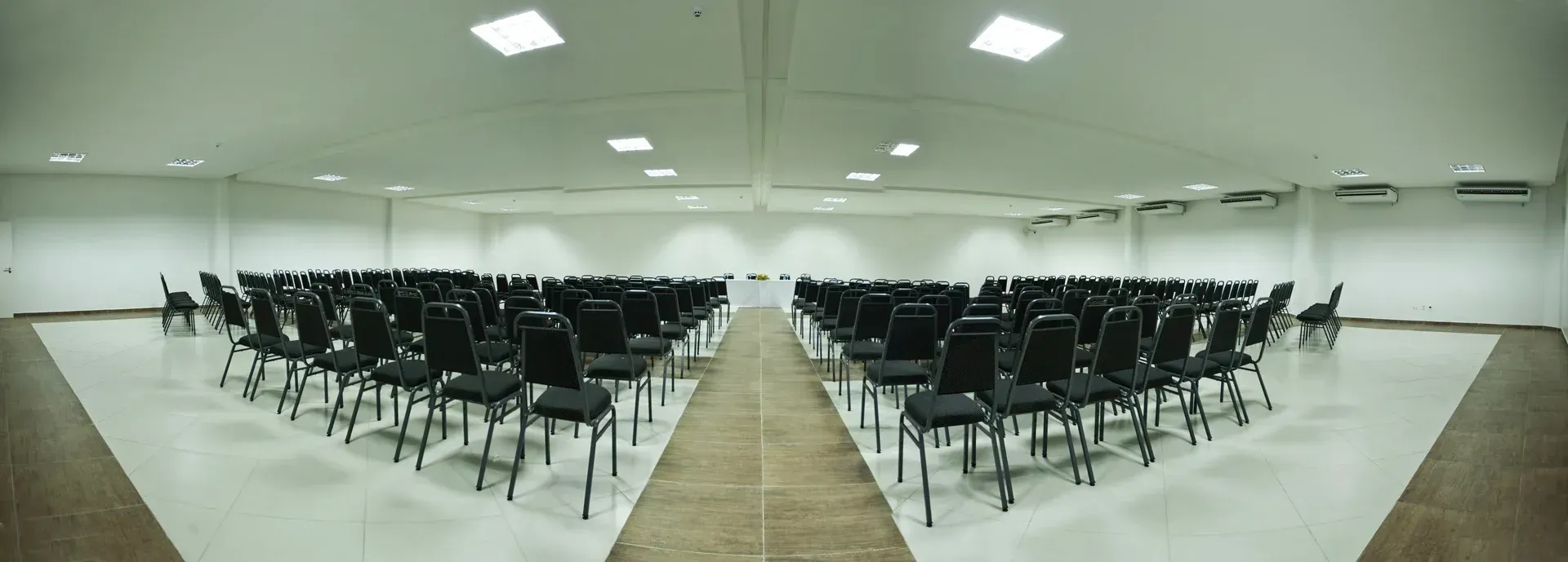 Fileiras de cadeiras estão dispostas em um triângulo em uma sala grande.