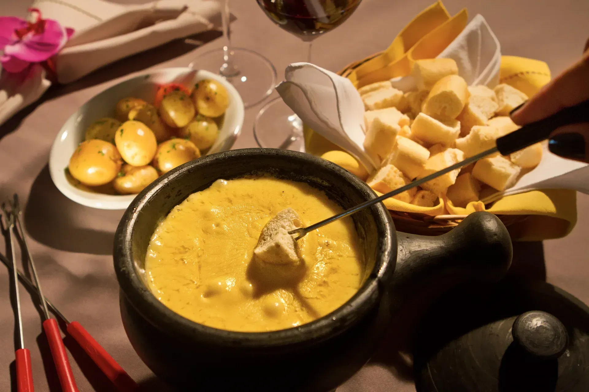Uma pessoa está mergulhando um pedaço de queijo em uma tigela de fondue