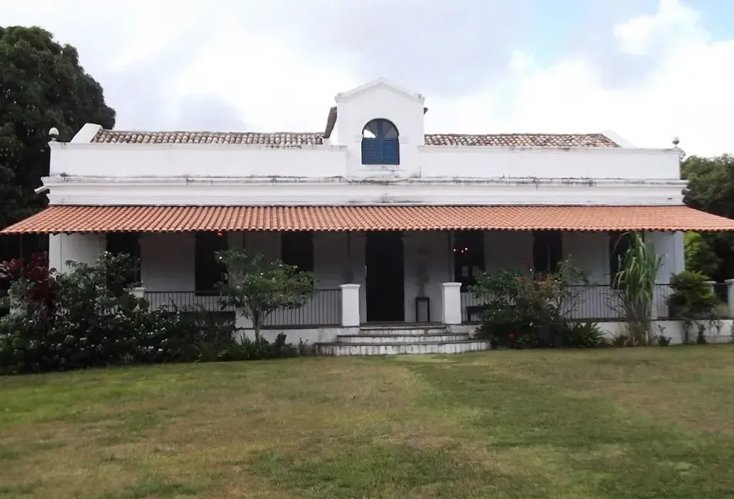 Uma casa branca com um telhado vermelho e uma varanda
