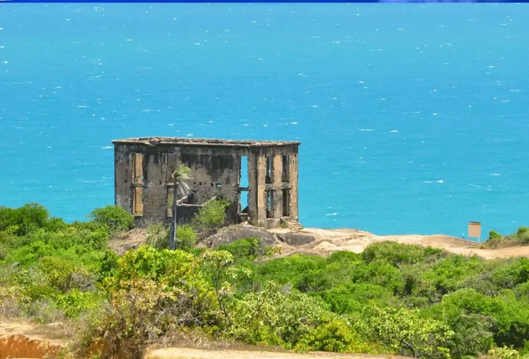Um prédio antigo fica no topo de uma colina perto do oceano.