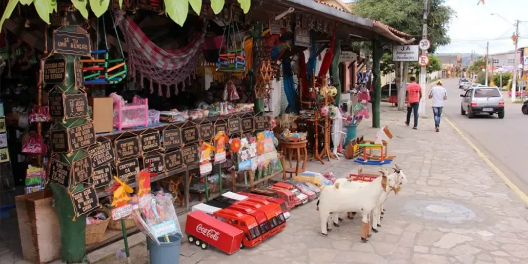 Uma cabra está parada em frente a uma loja na beira da estrada.