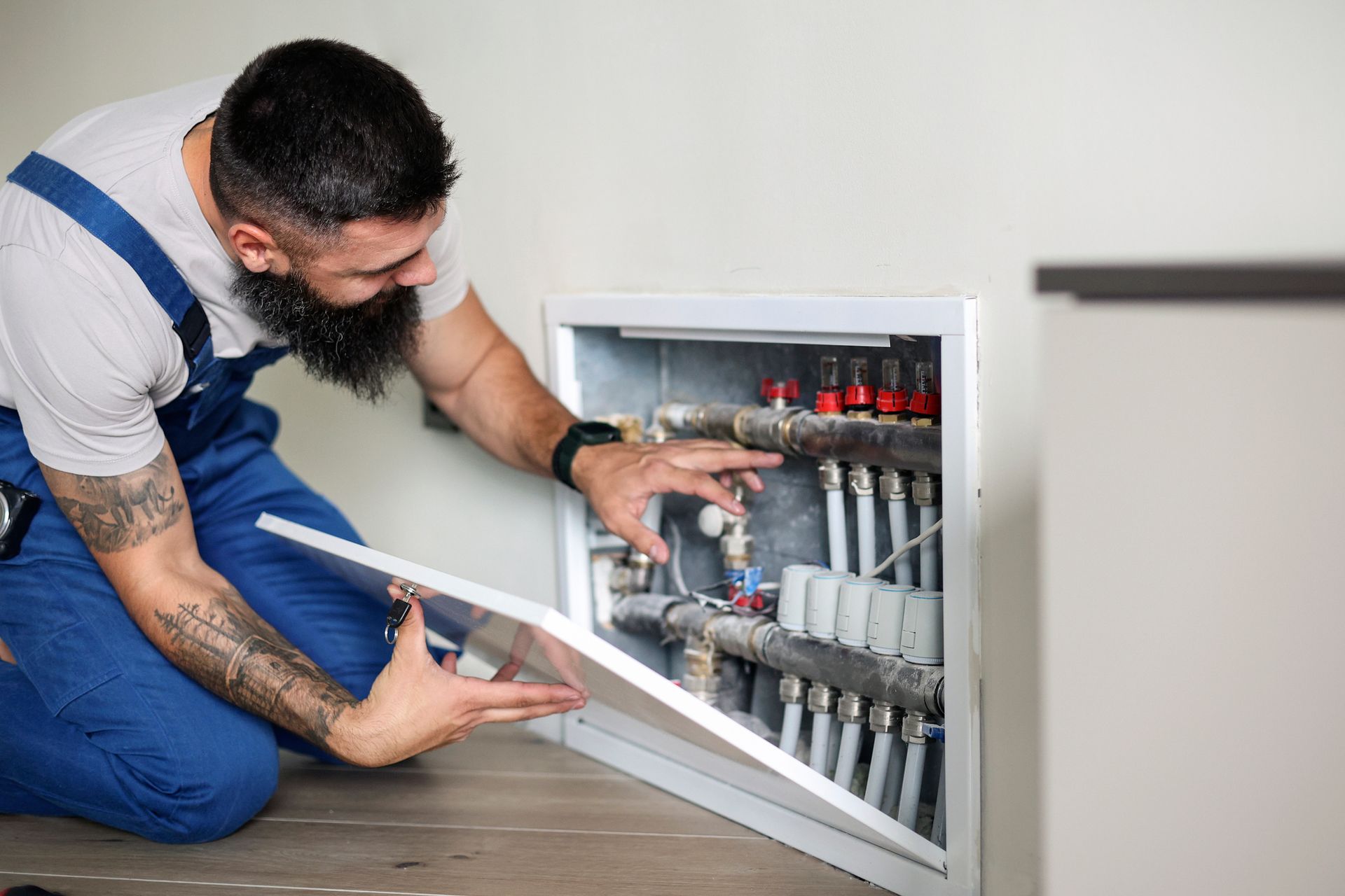 A man is fixing pipes in a room, showcasing his expertise as a heating repair contractor.