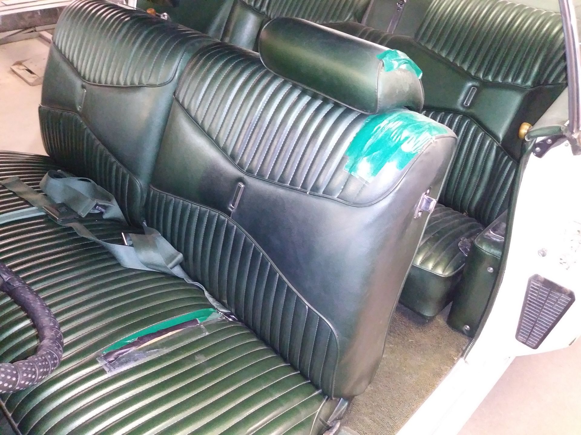 Black-and-green striped car seats with teal worn patches inside a vehicle