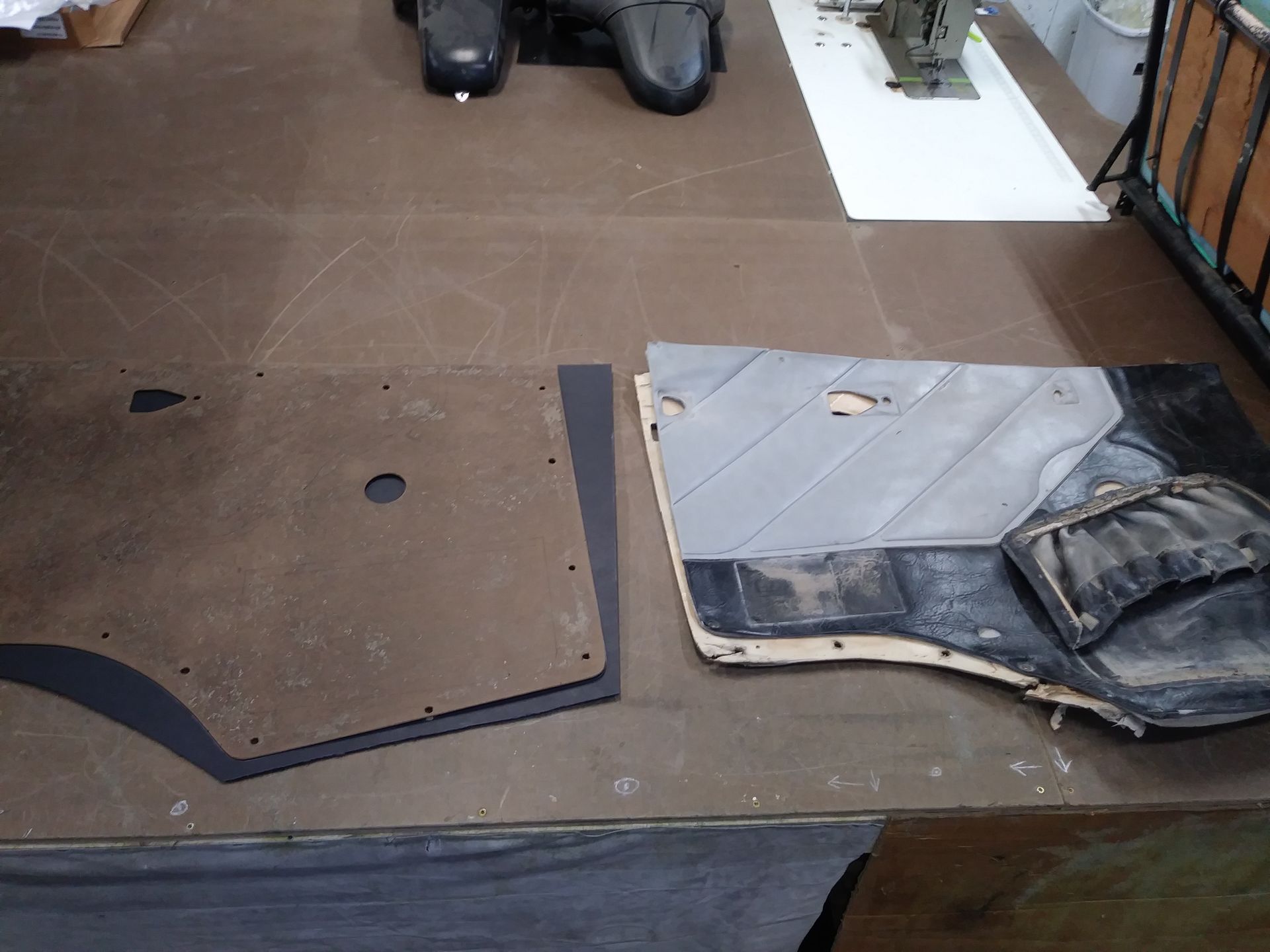 Two black interior trim panels laid out on a brown work surface, one flat and one curved.