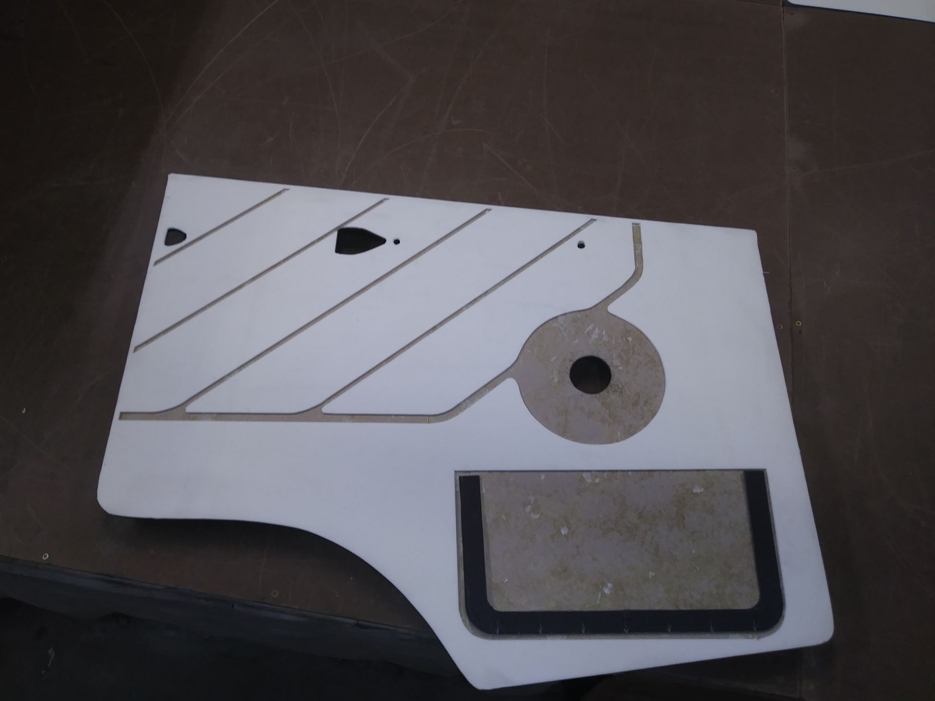 White mechanical part with diagonal grooves, a circular hole, and a black rectangular inset on a dark surface