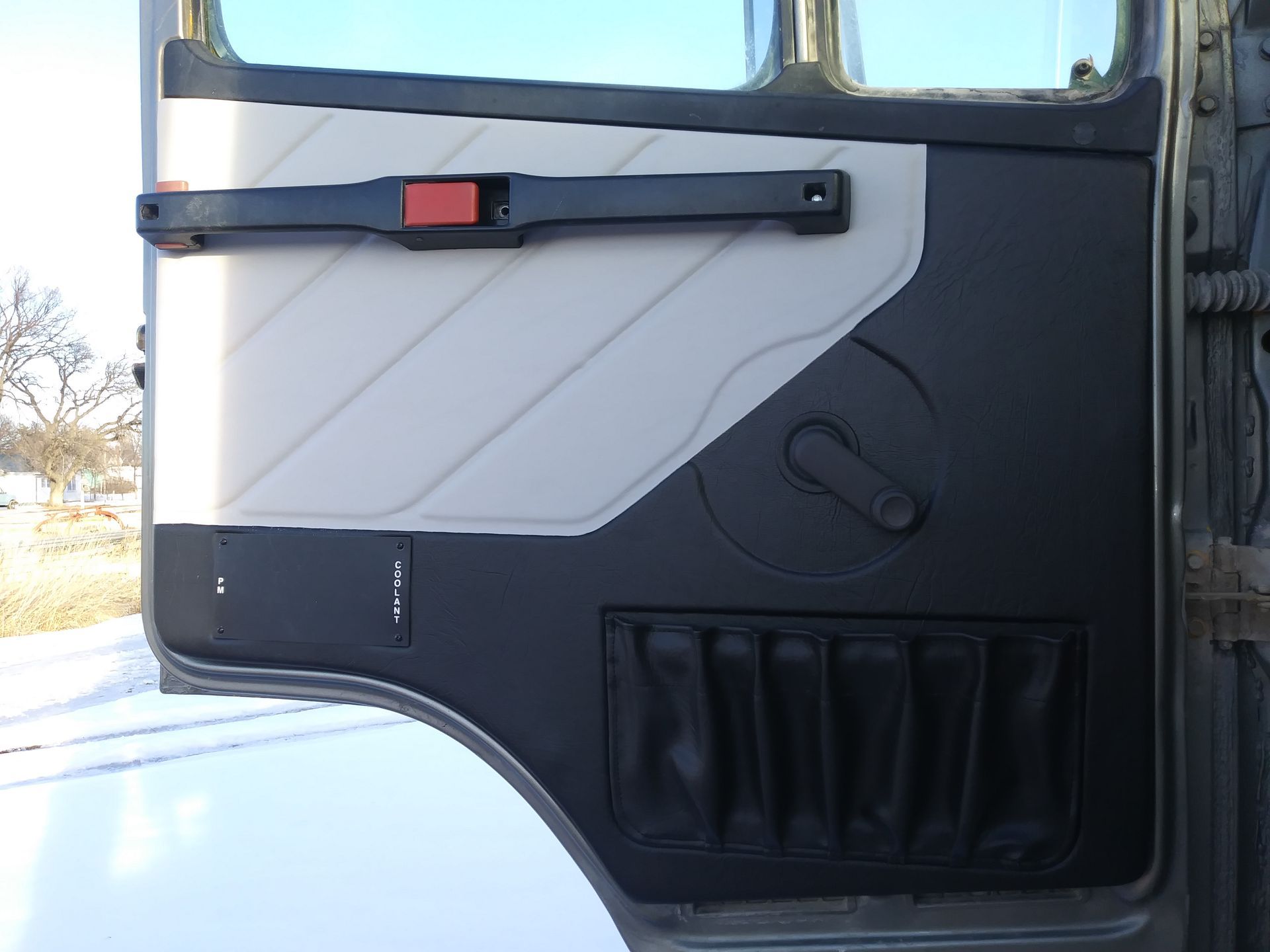 Truck cab interior door panel in white and dark gray, with handle, latch, and storage pocket.