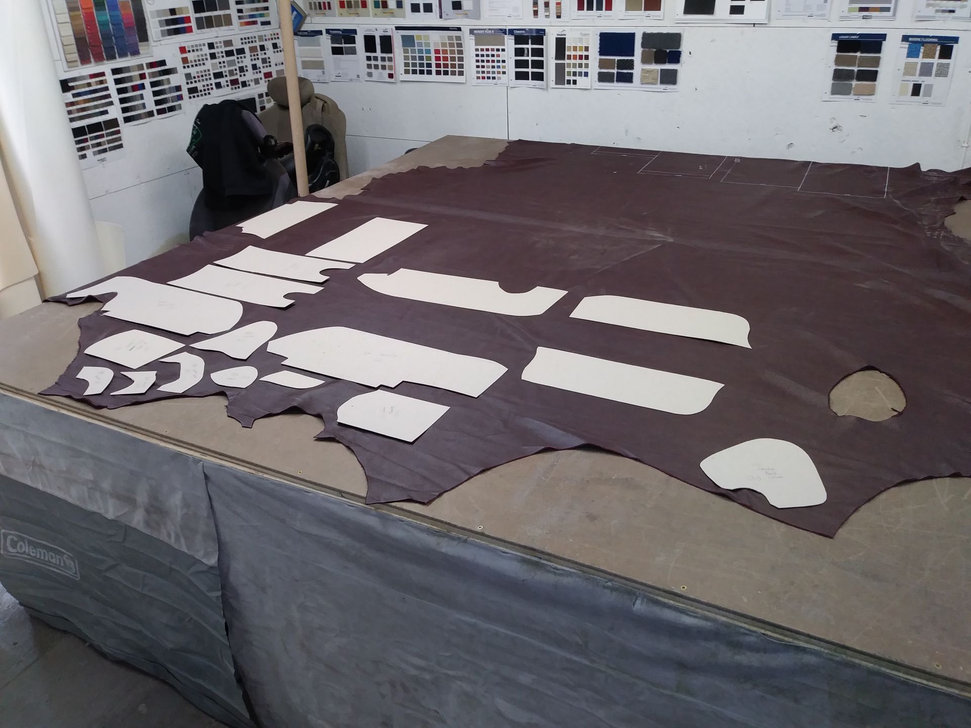 Fabric pattern pieces laid out on a large brown cloth in a sewing studio