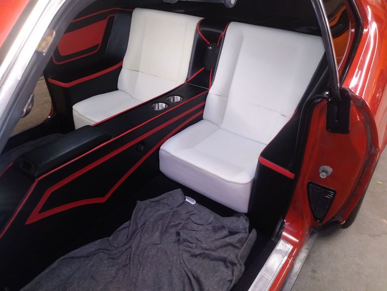 Custom car interior with white seats, black-and-red trim, and a dark floor mat inside an orange vehicle